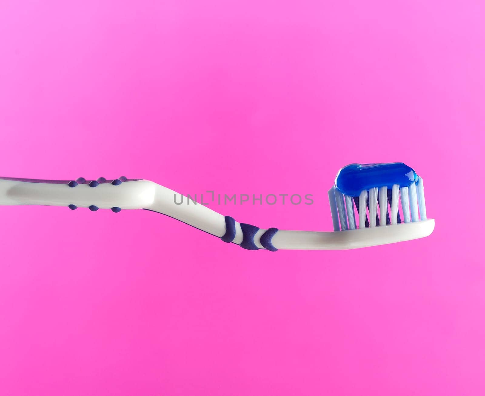 Toothbrush with toothpaste on pink background