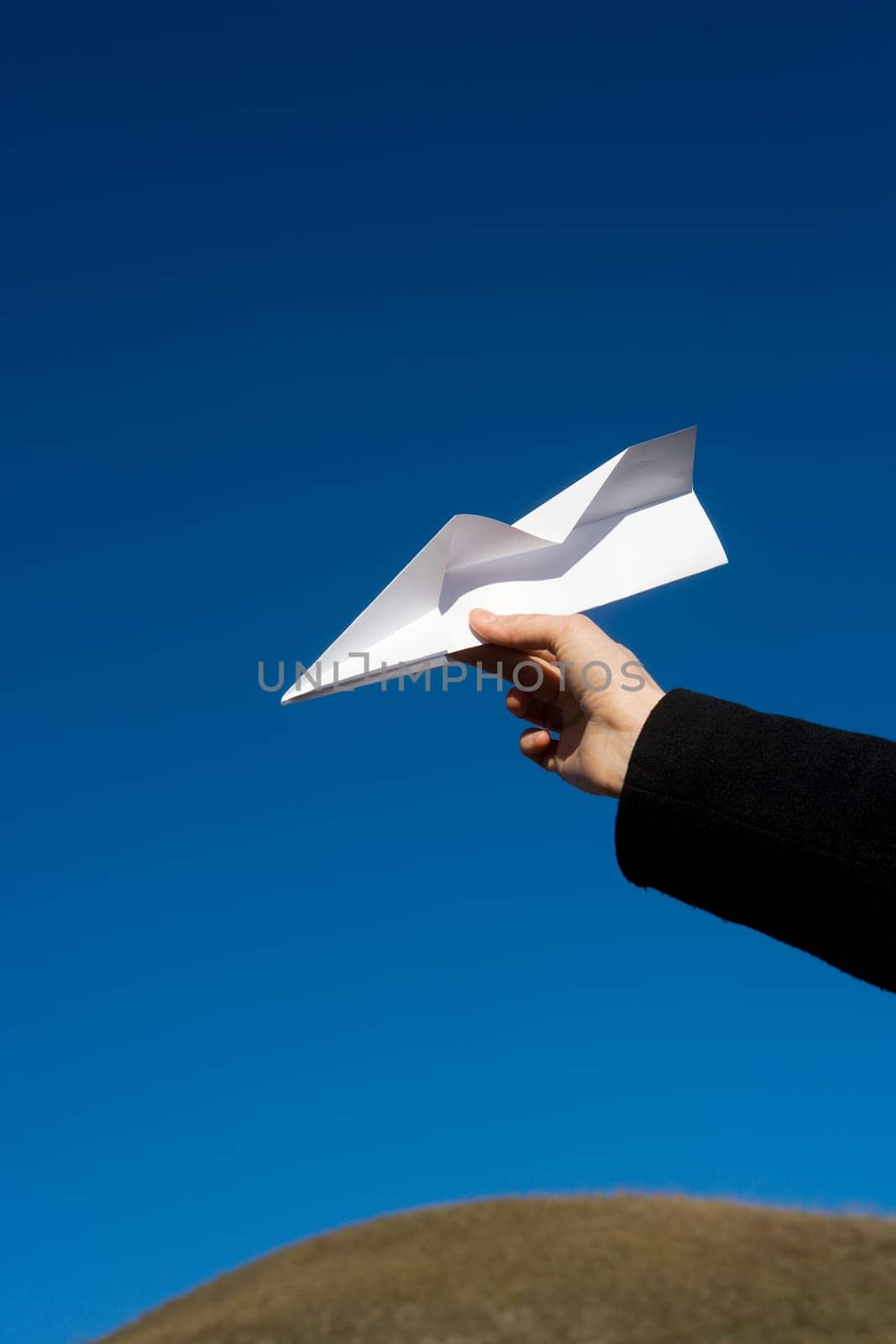 Hand holding a Paper Airplane towards blue sky