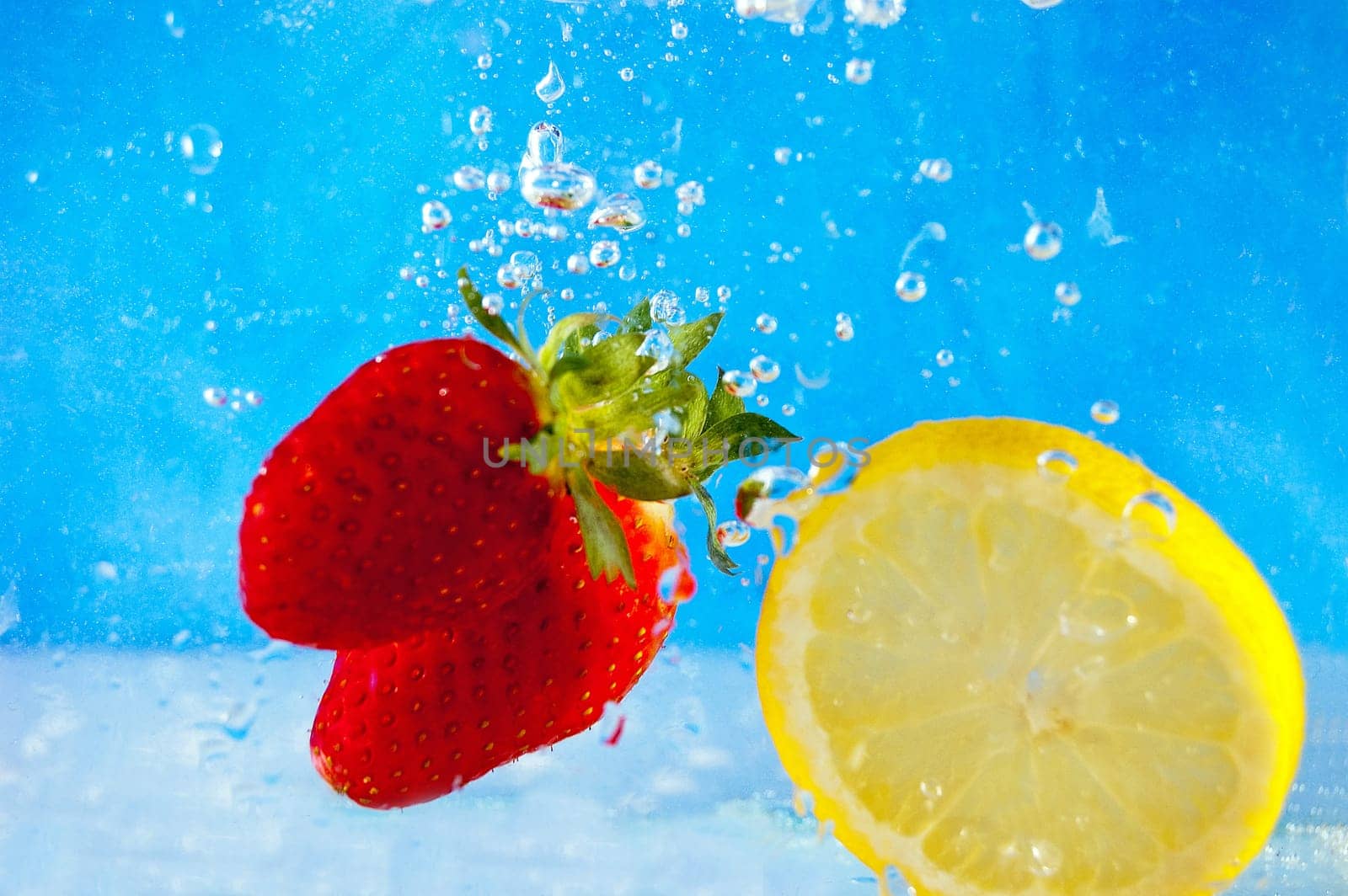 Fresh fruits falling into the water on a blue mosaic background