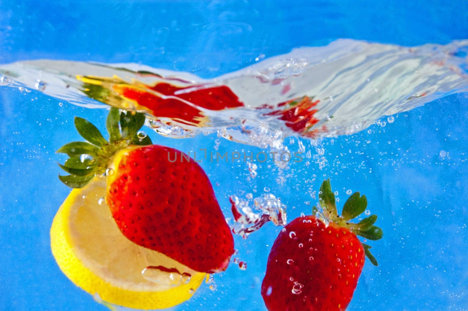 Fresh fruits falling into the water on a blue mosaic background
