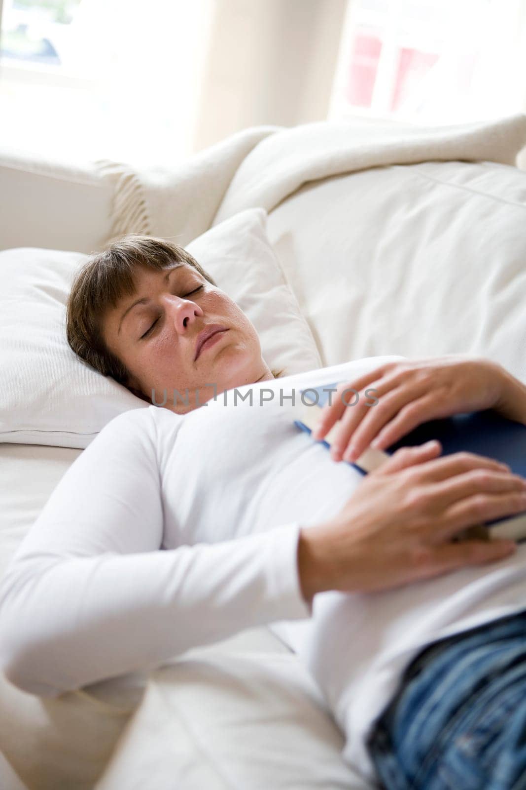 Sleeping woman in the sofa with a book