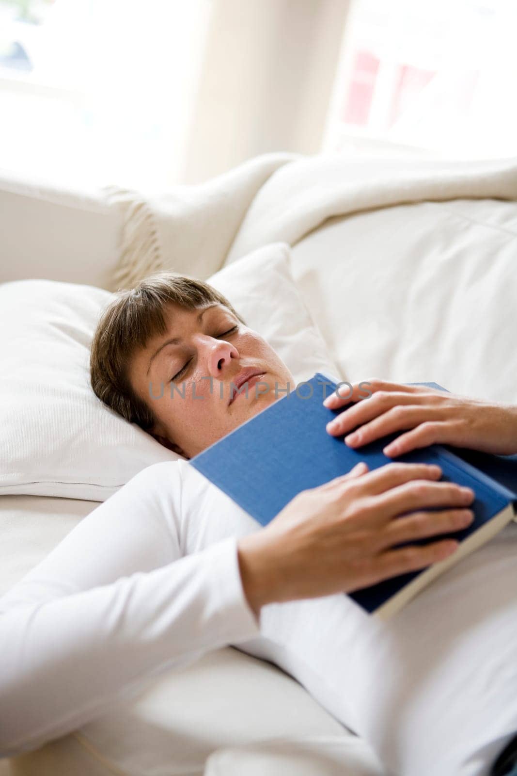 Sleeping woman in the sofa with a book
