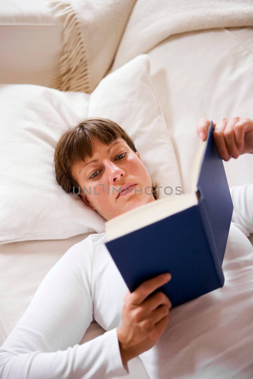 Woman in the sofa reading a book