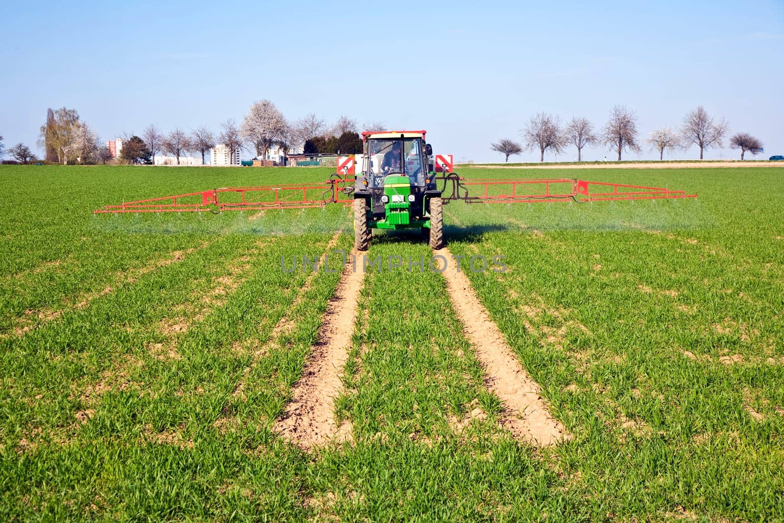 tractor on field sputtering pest protection on plants