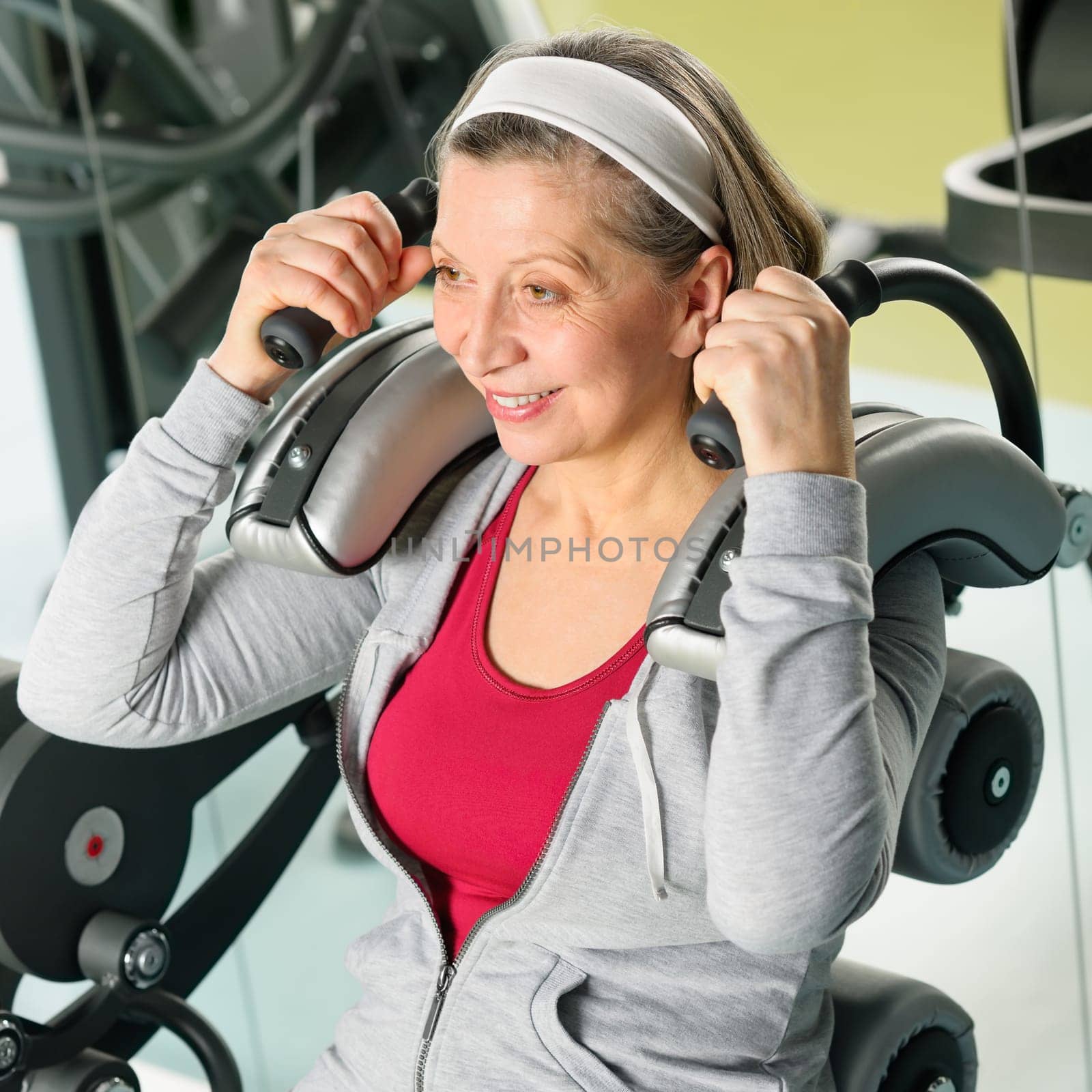 Fitness center senior woman exercise smiling on gym machine