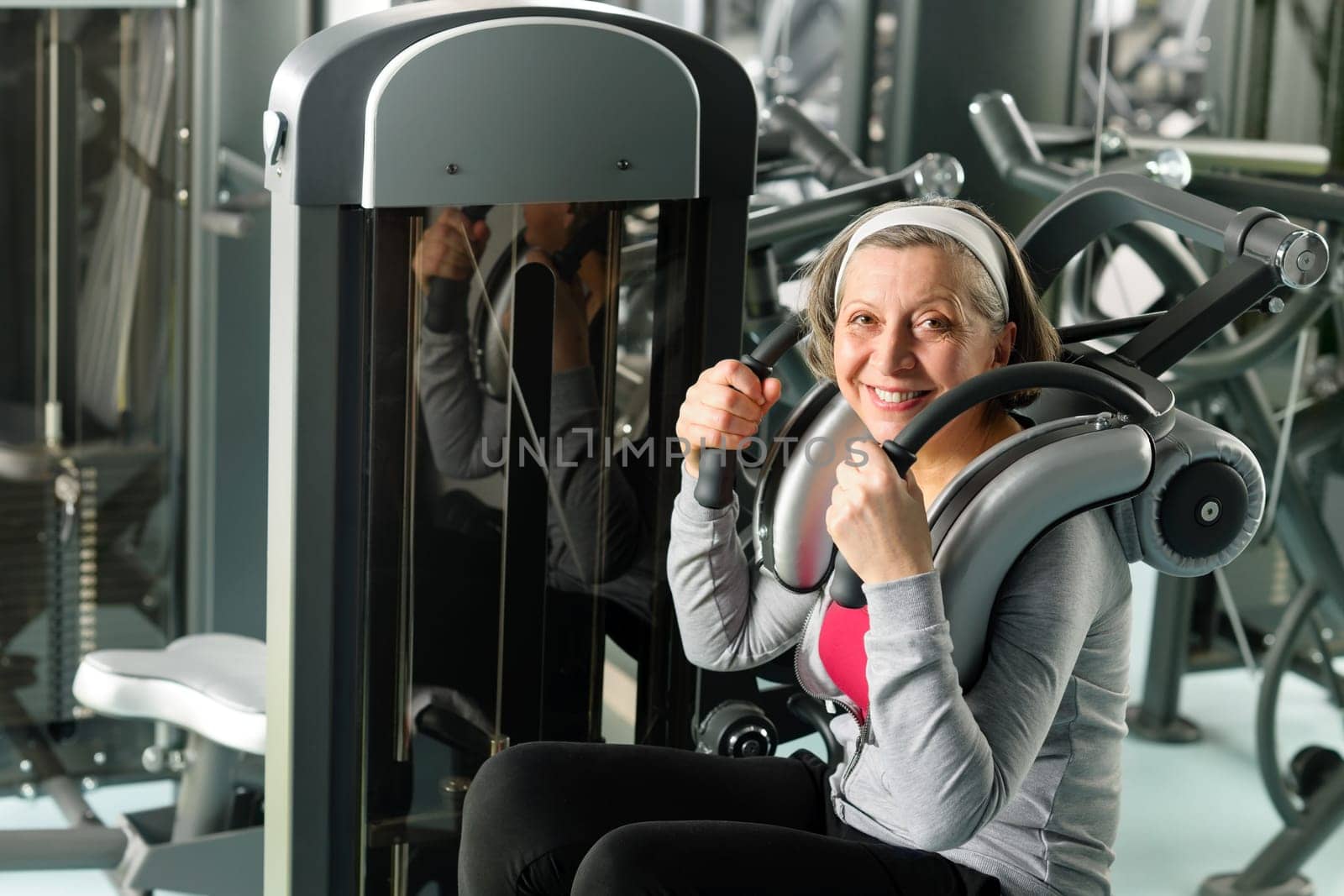 Fitness center senior woman exercise smiling on gym machine