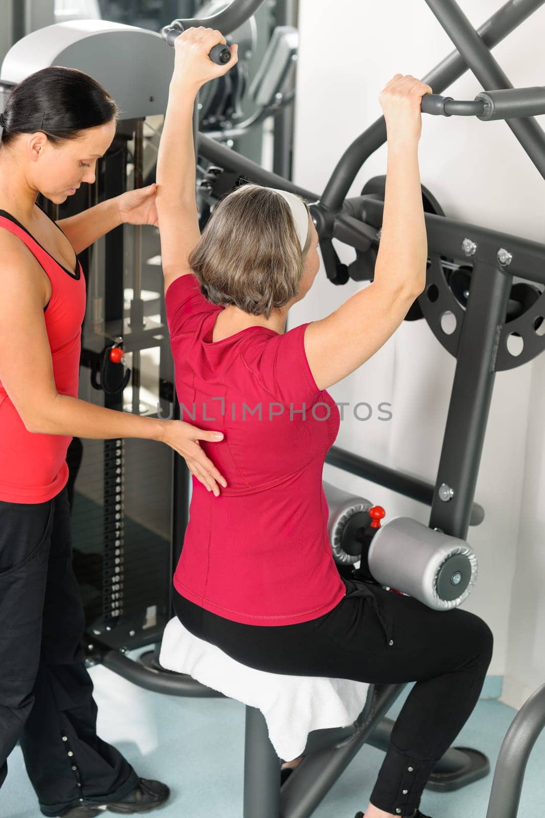 Fitness center personal trainer senior woman exercise shoulder on machine