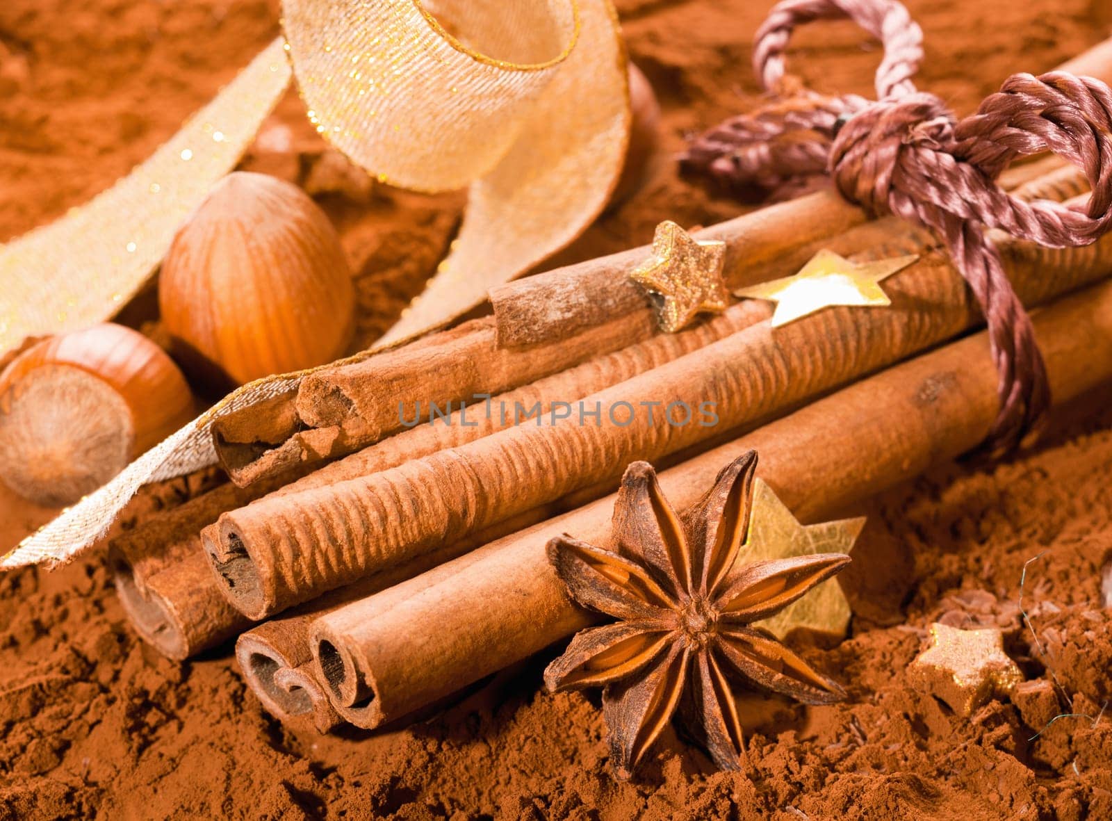 Bundle of Cinnamon with golden Stars, hazelnut and a bow on powdered cocoa