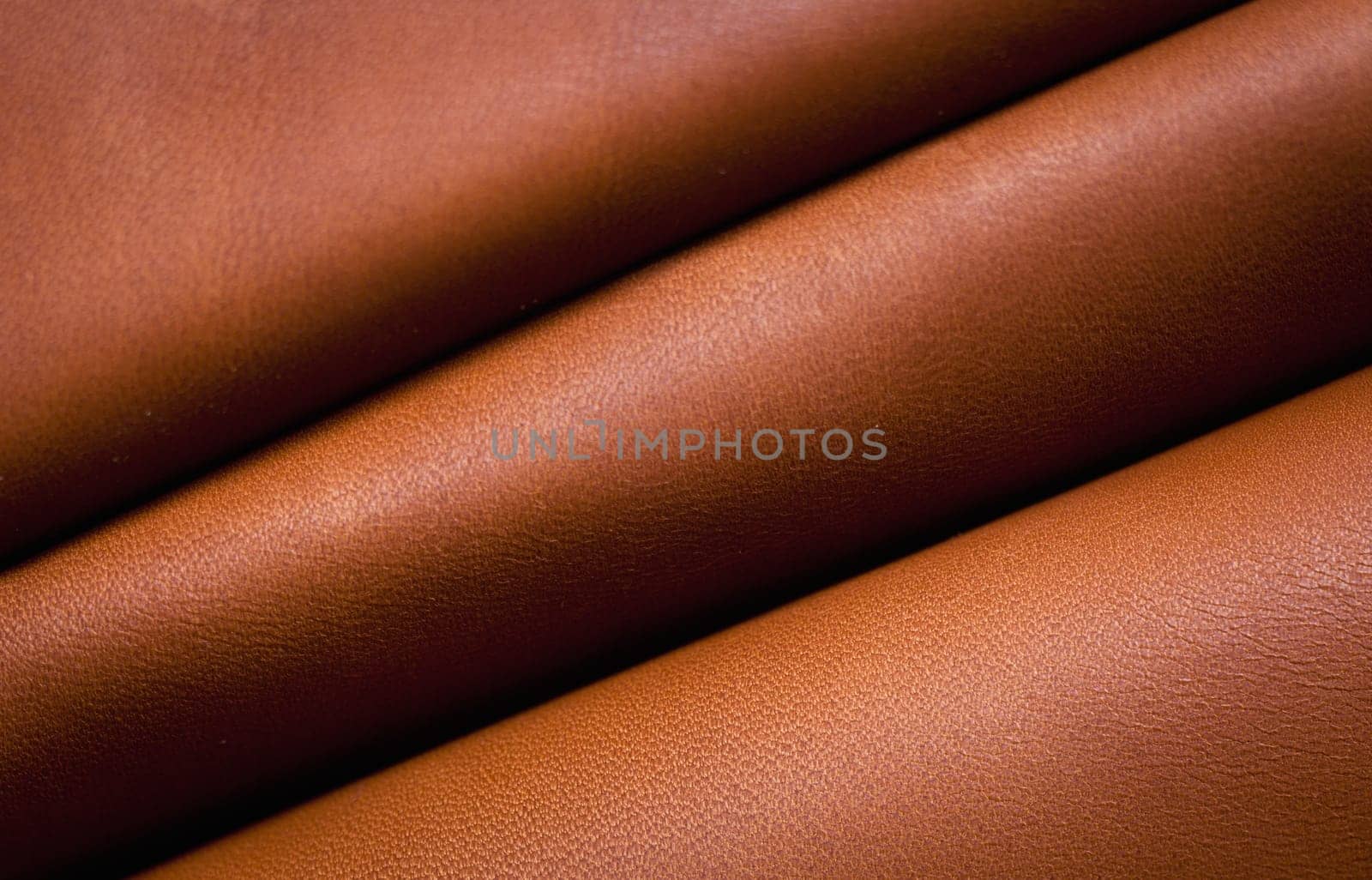 Abstract background of diagonally folded brown textured leather.