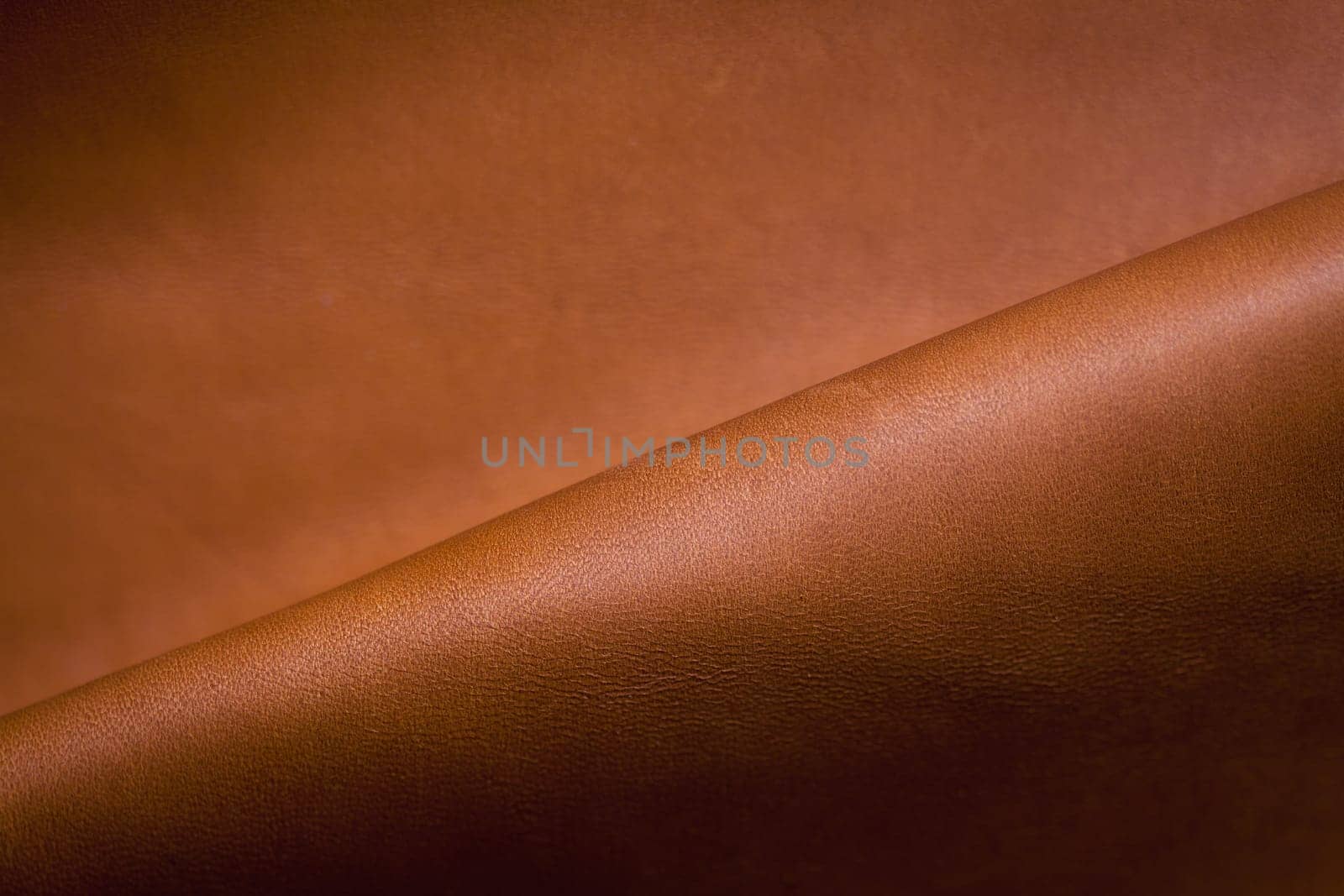 Abstract background of a section of brown leather with a single diagonal fold and copyspace