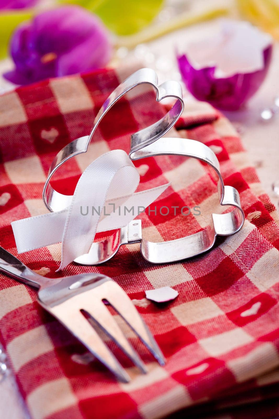 Cheerful country Easter table setting with a silver metal bunny rabbit on a red checked tablemat