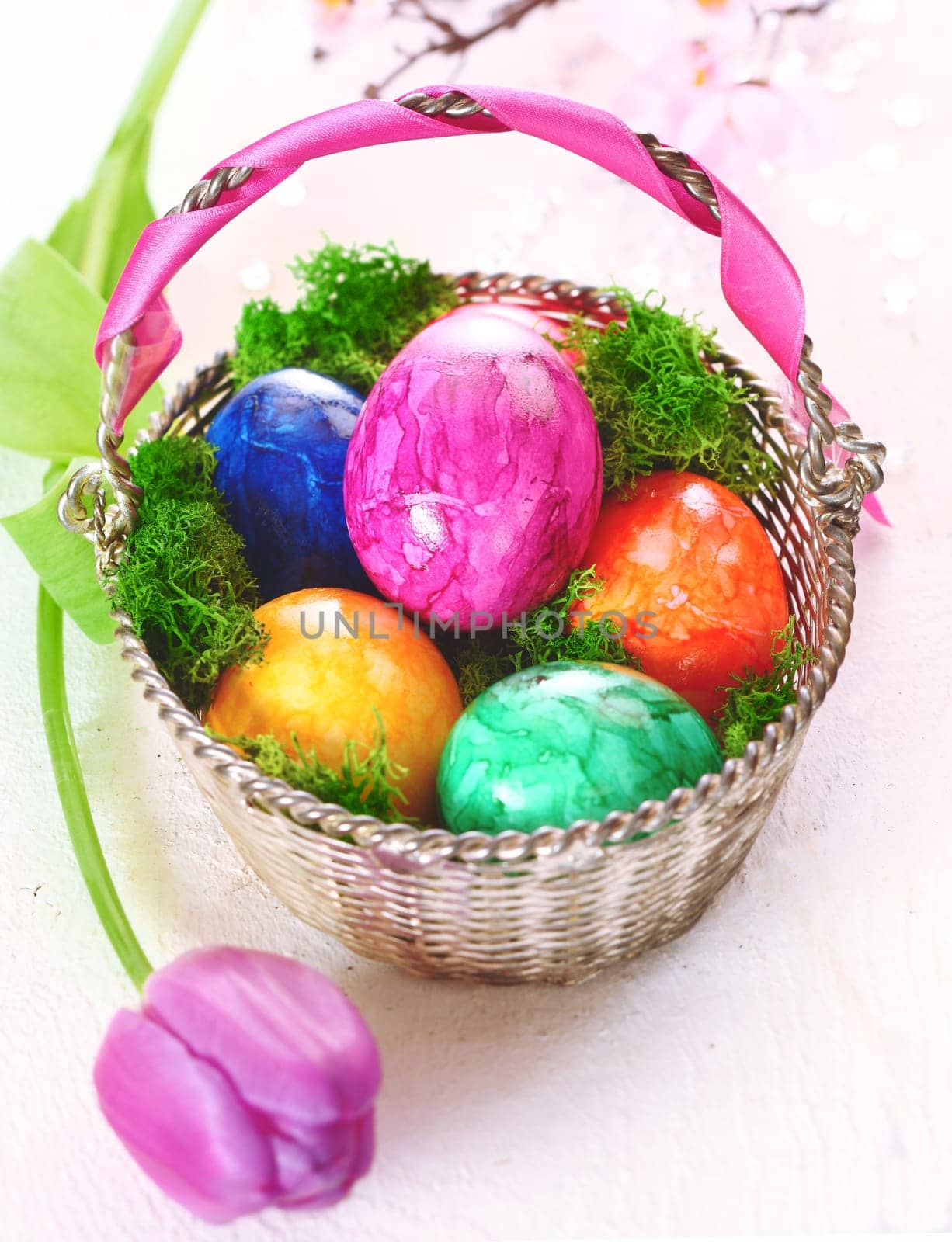 A basket full of colourful dyed marbled Easter eggs with a pretty pink tulip