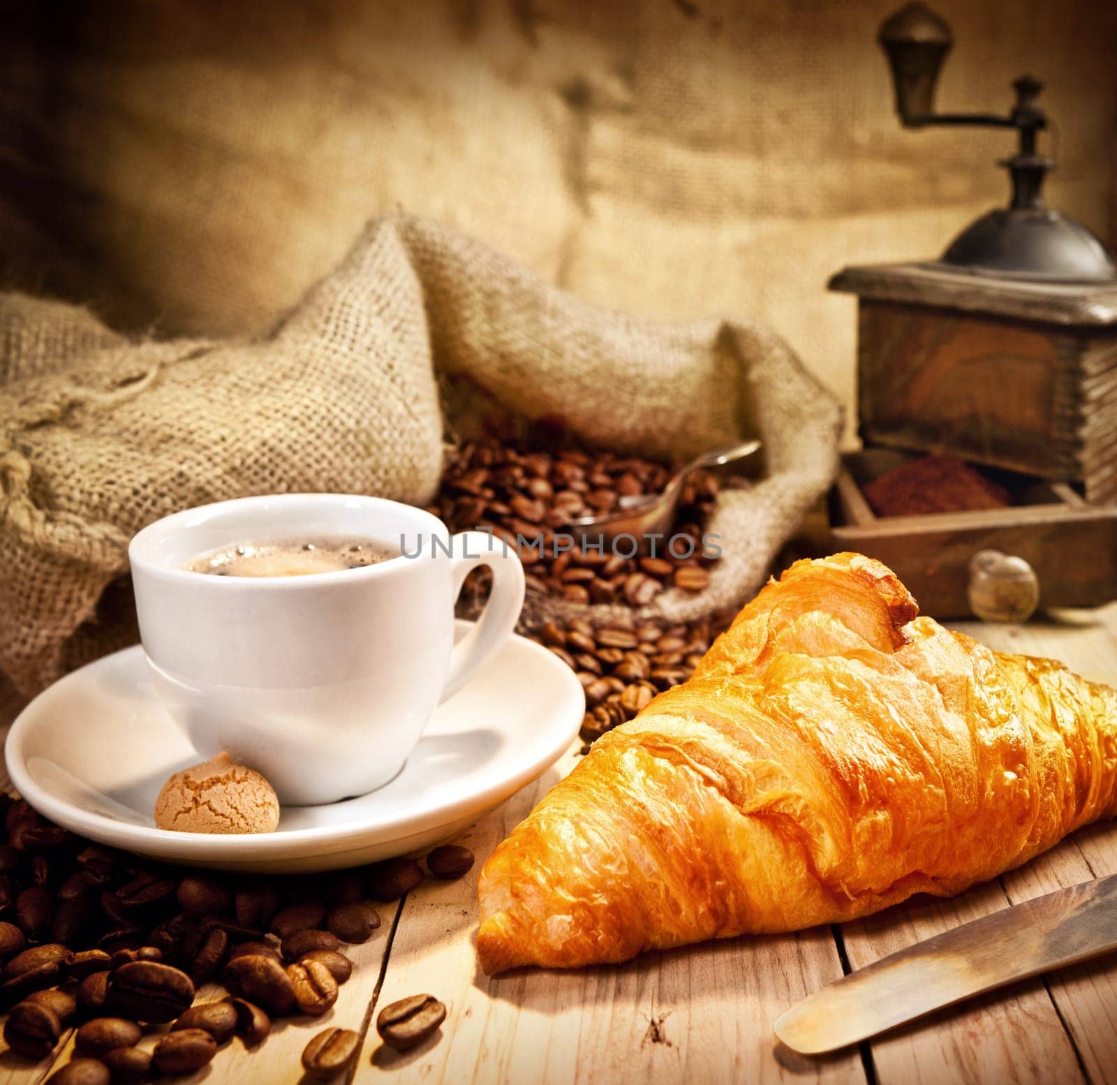 Coffee cup with a croissant and fresh coffee beanson a brown background