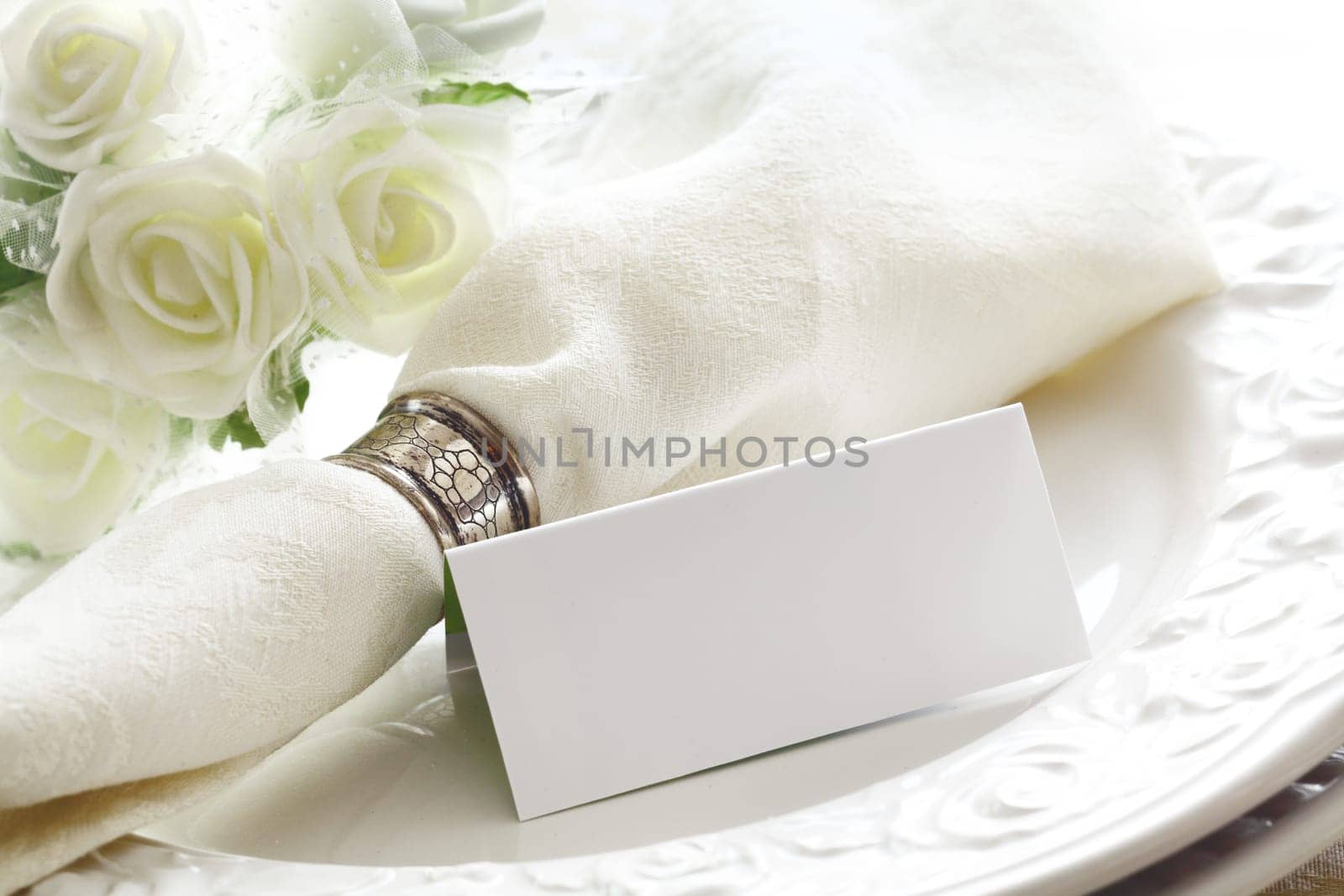 Elegant white Wedding place setting with beautiful white roses and a blank card