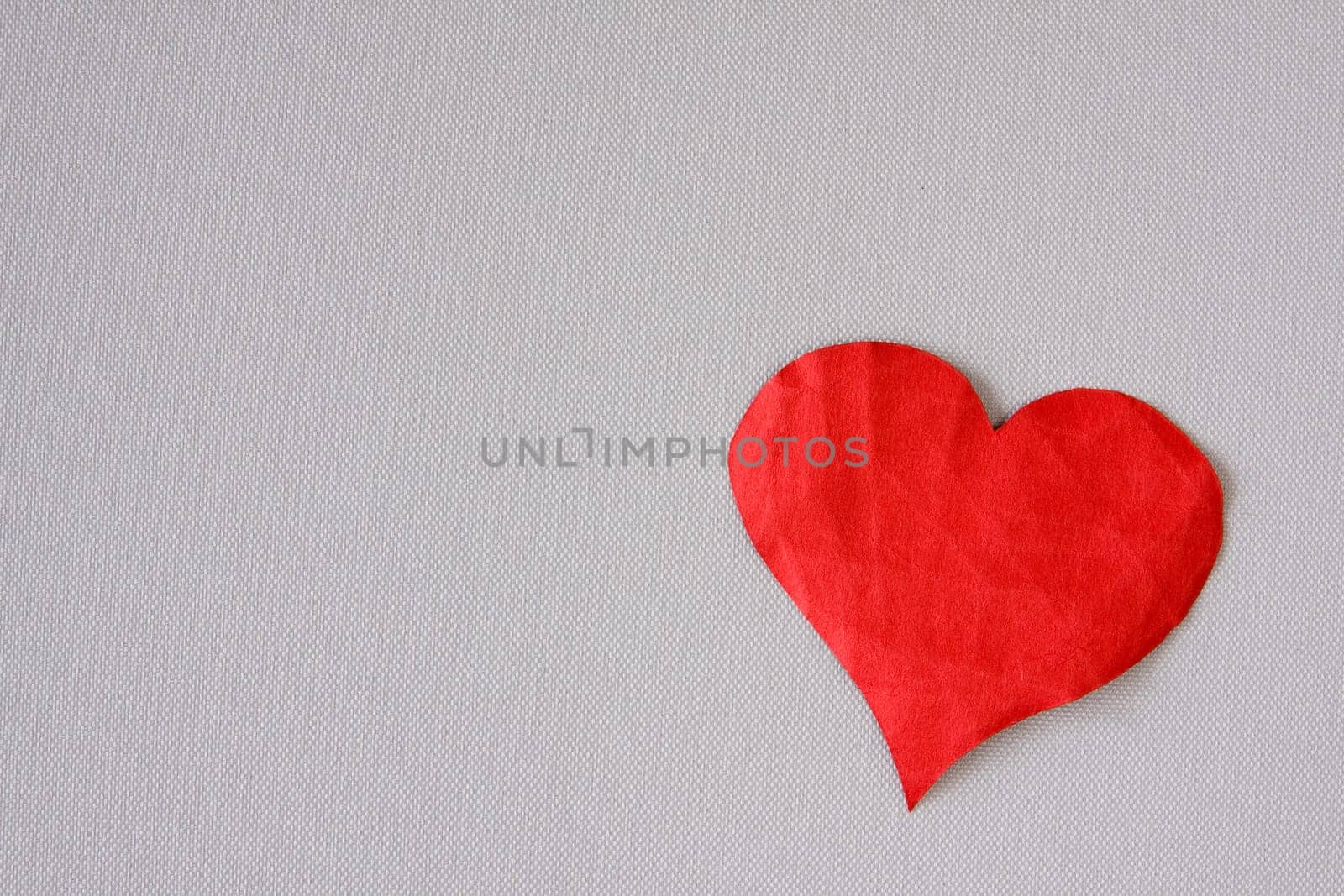 Crumpled red paper heart on a grey background