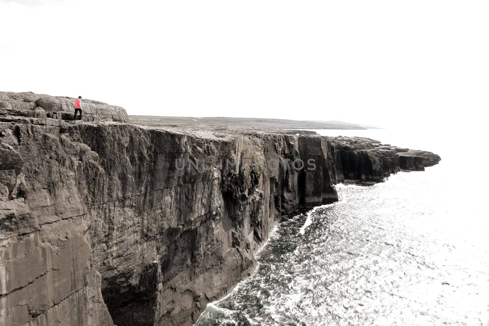 lone person on the cliffs edge on a rocky landscape of the burren in county clare ireland