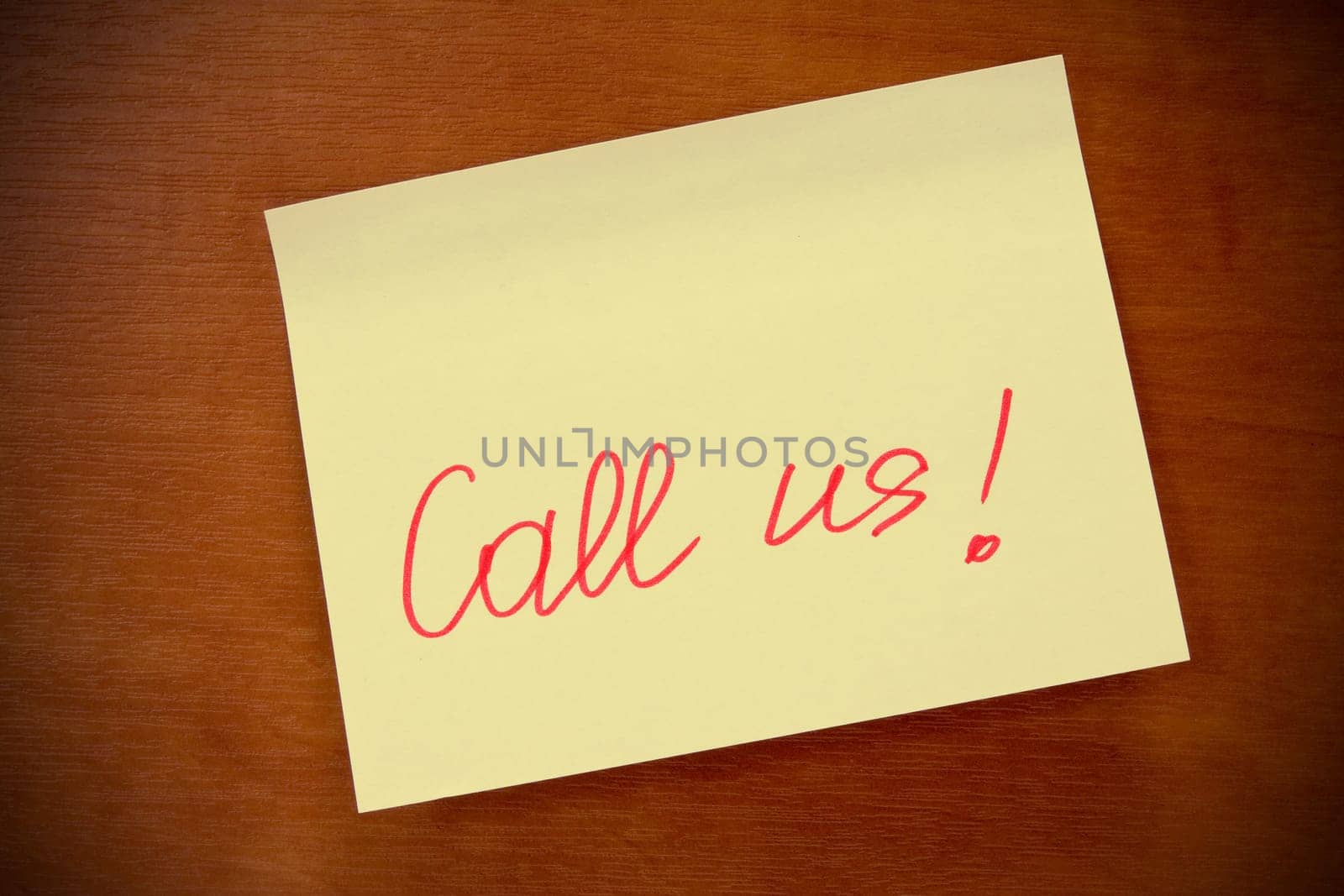 wooden board with yellow sticky note "call us"""