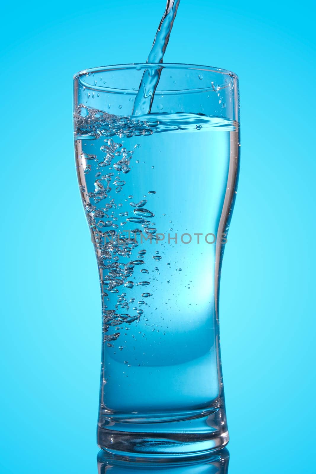 pouring water into a glass. isolated on blue background
