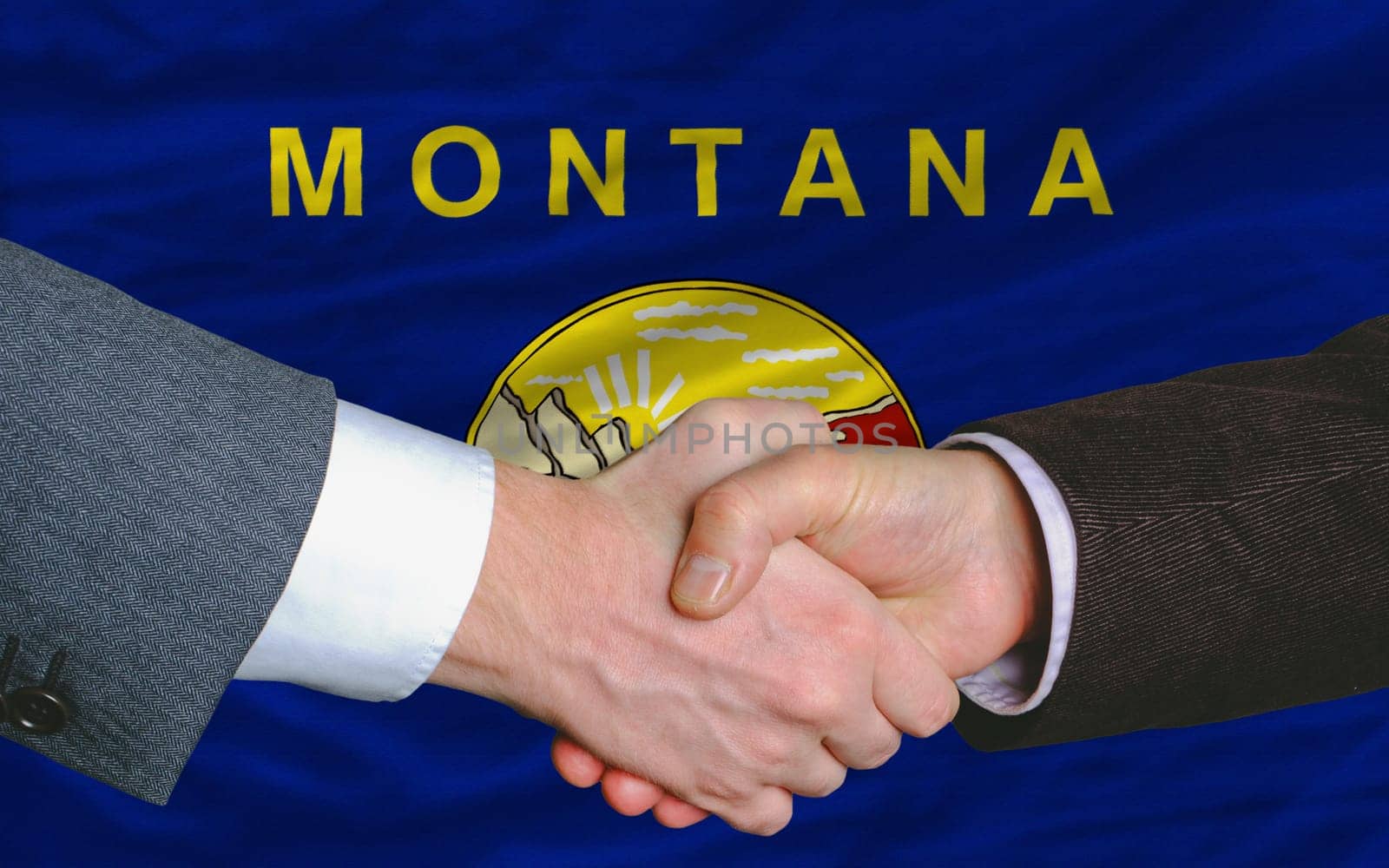 two businessmen shaking hands after good business investment agreement in front US state flag of montana