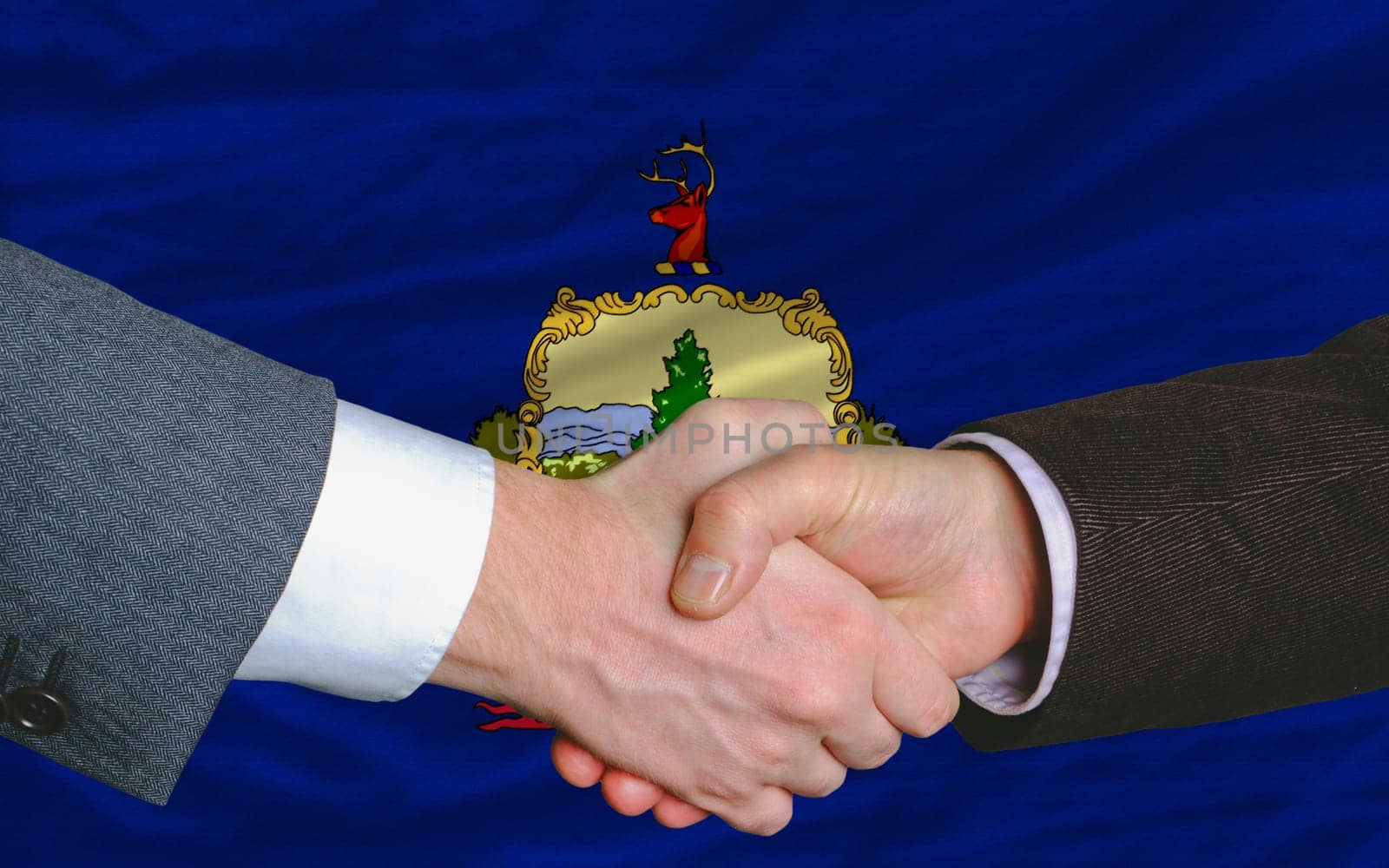two businessmen shaking hands after good business investment agreement in front US state flag of vermont