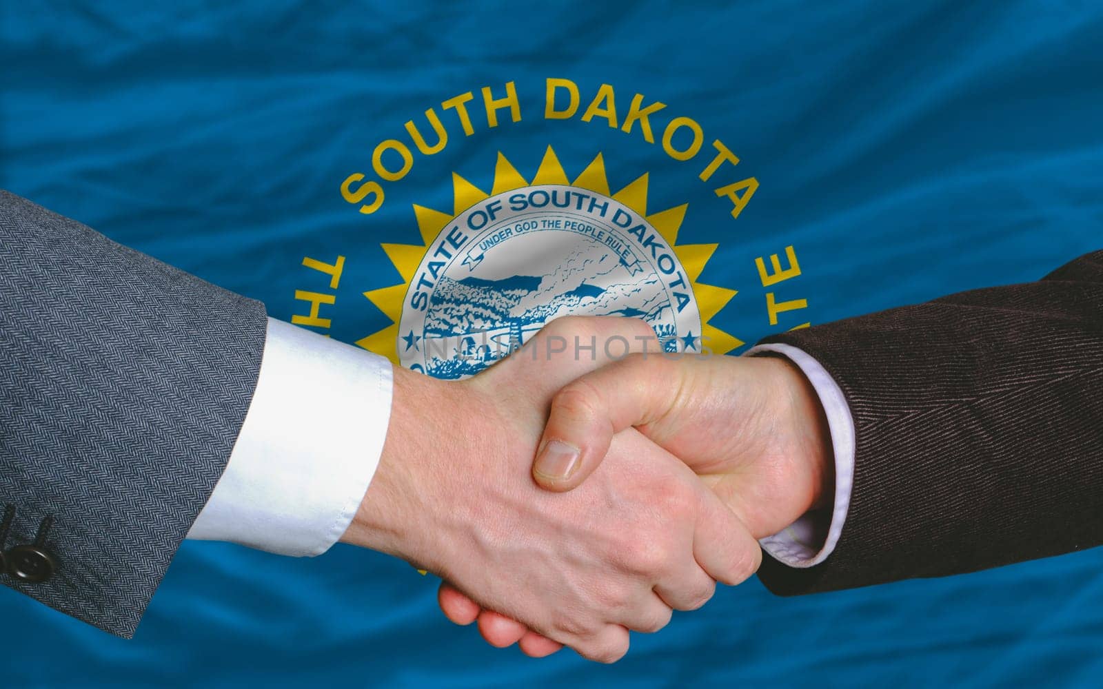 two businessmen shaking hands after good business investment agreement in front US state flag of south dakota