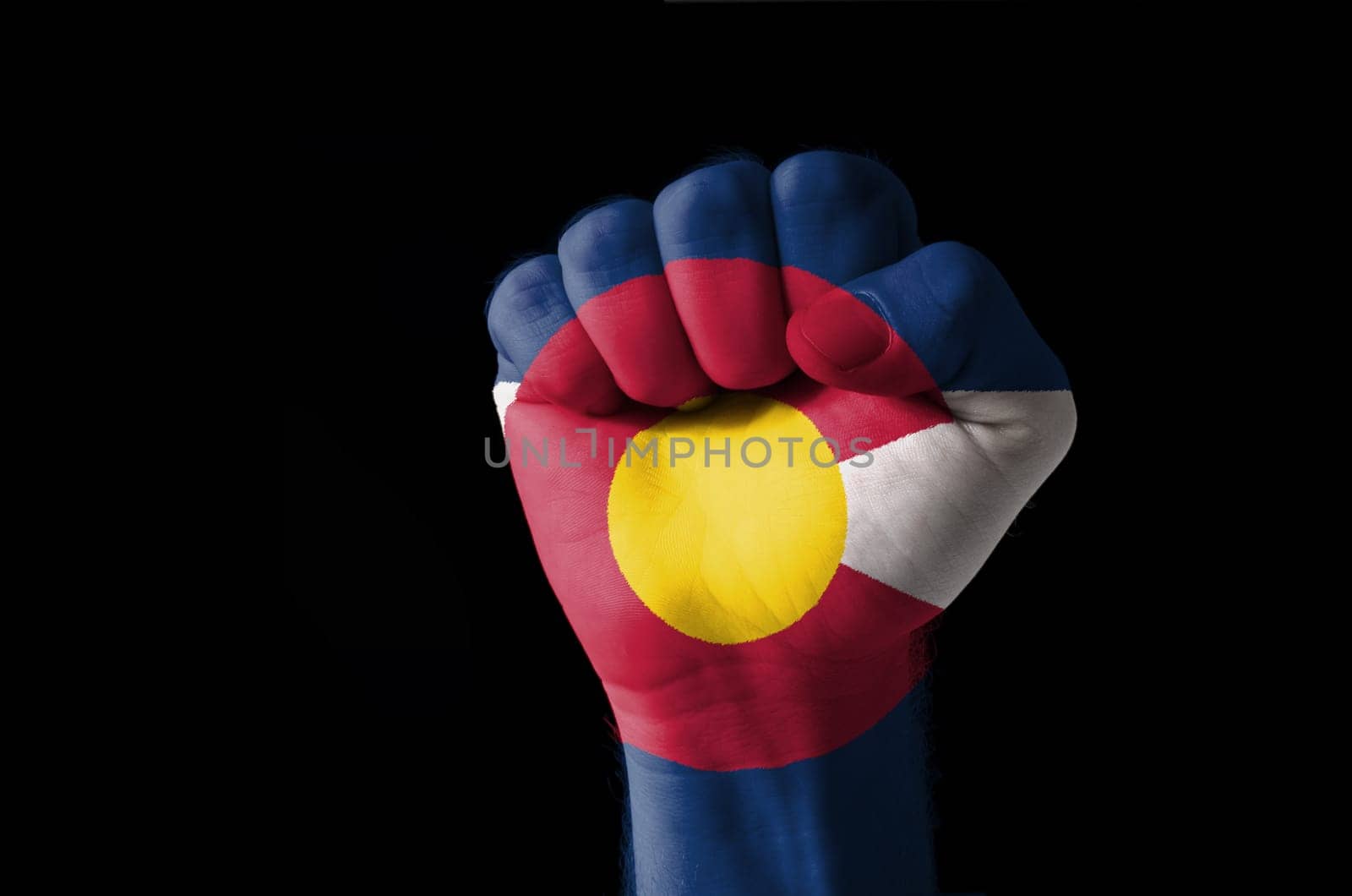 Low key picture of a fist painted in colors of american state flag of colorado