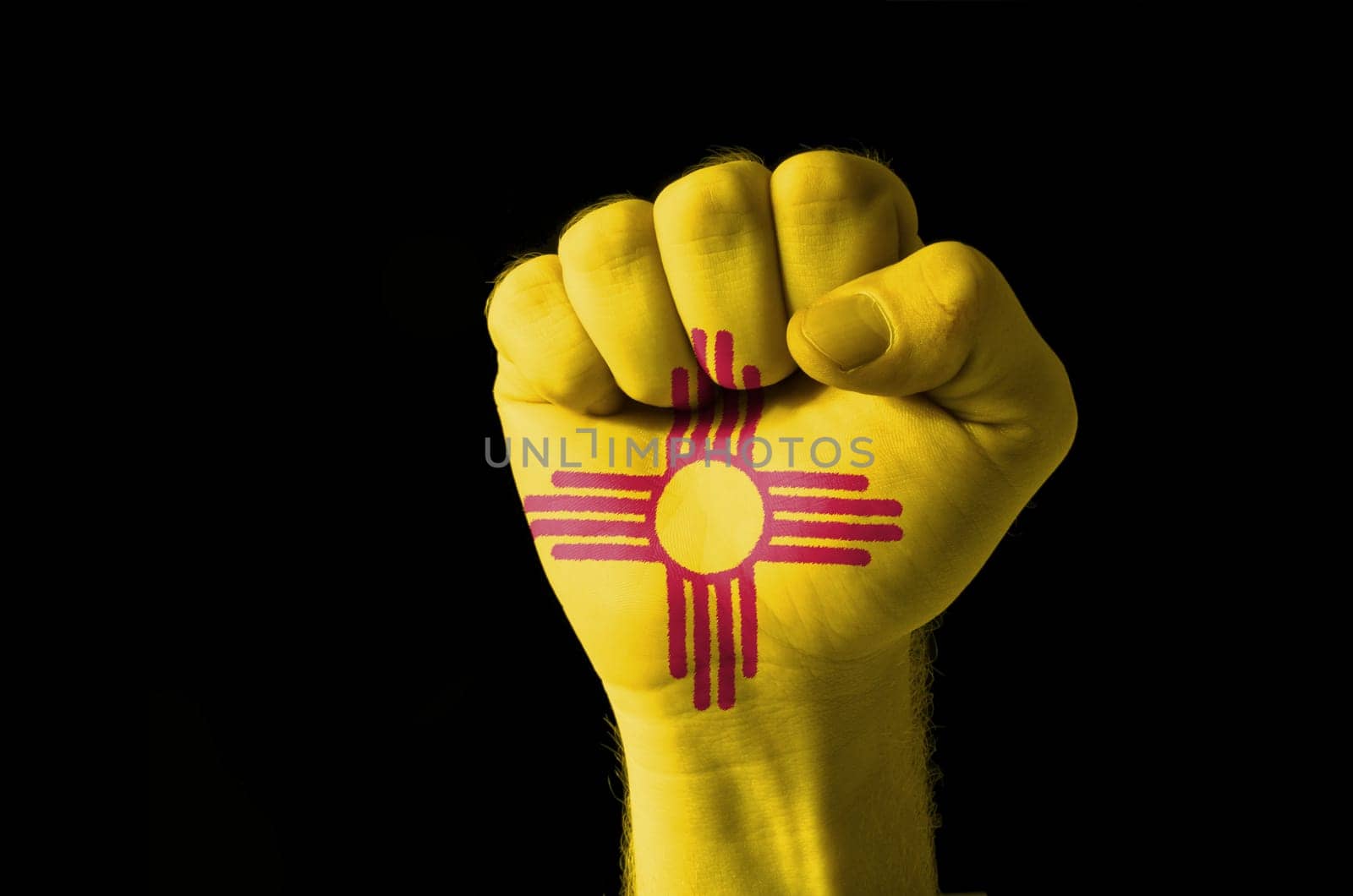 Low key picture of a fist painted in colors of american state flag of new mexico