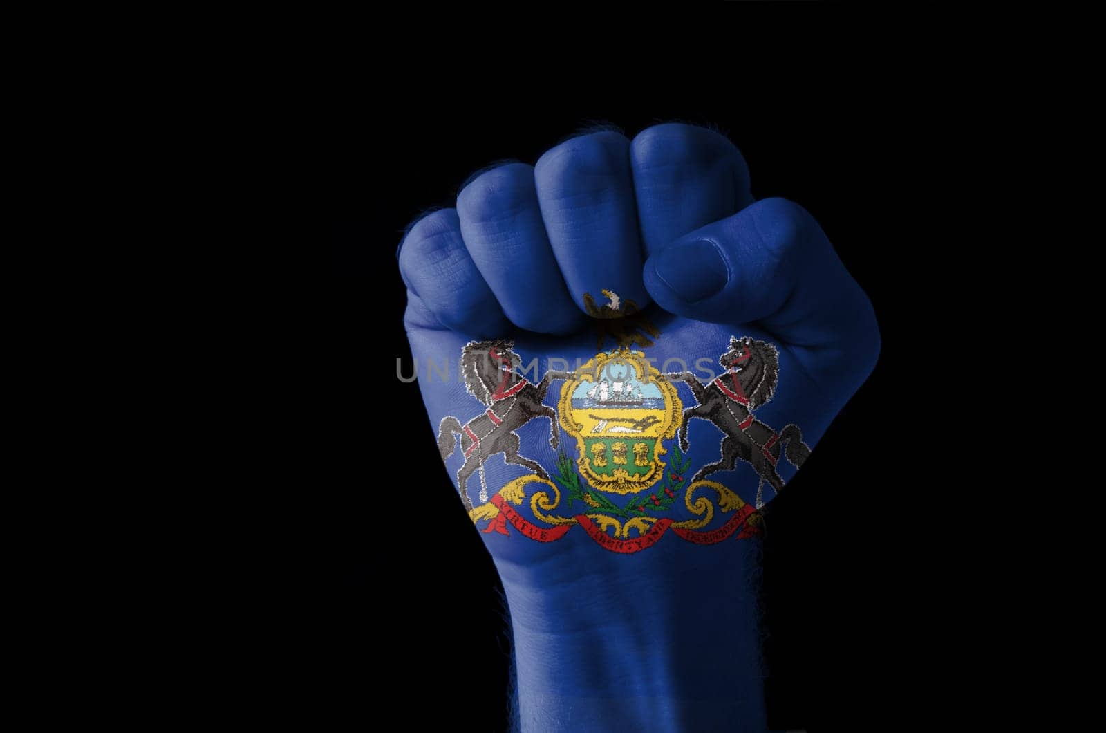 Low key picture of a fist painted in colors of american state flag of pennsylvania