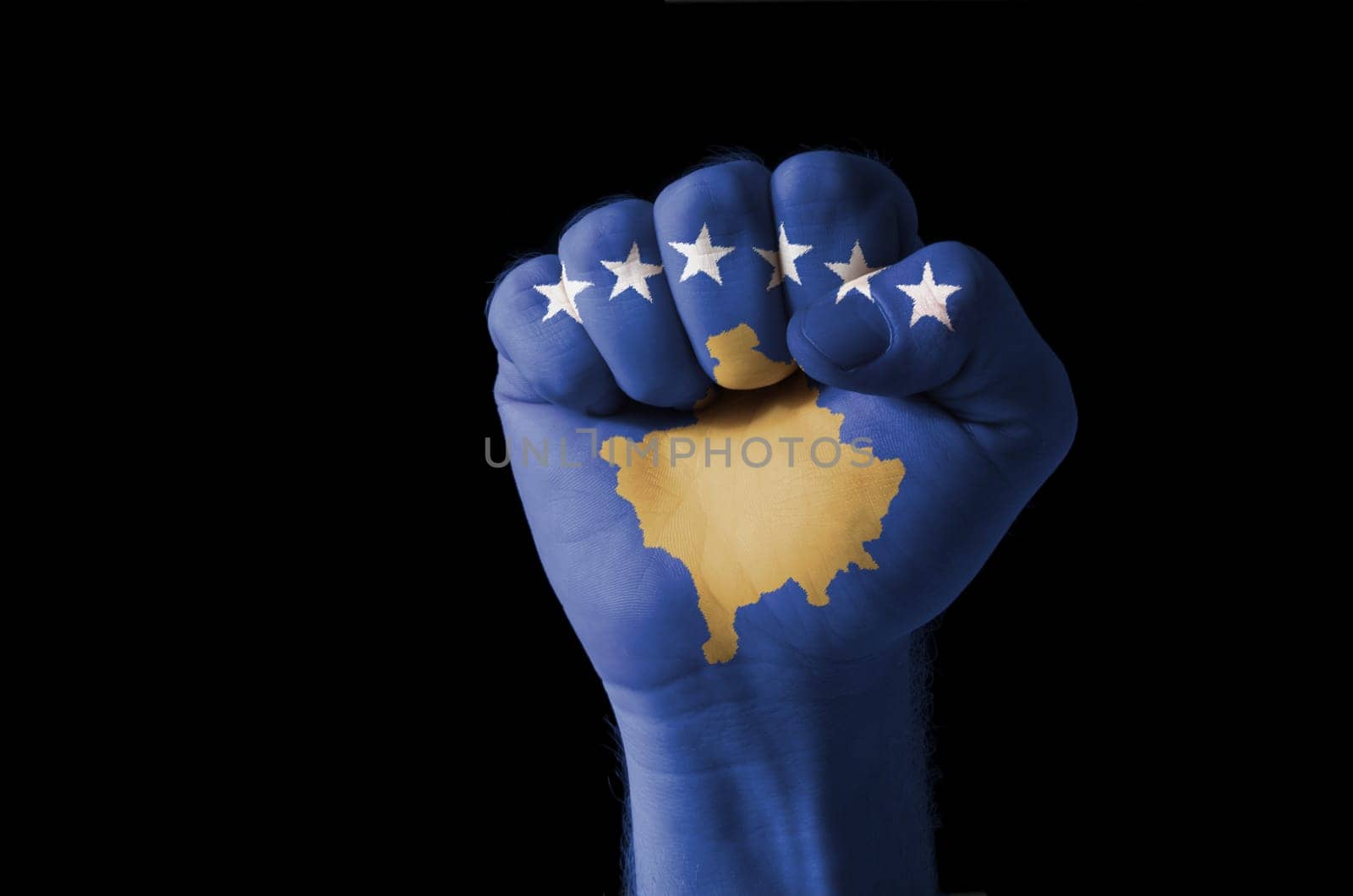 Low key picture of a fist painted in colors of kosovo flag