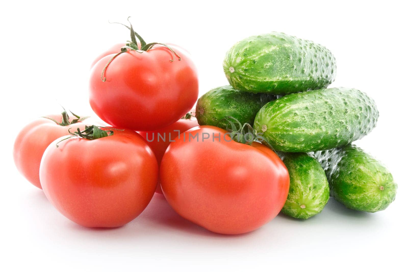 Fresh raw tomatoes and cucumbers over a white background