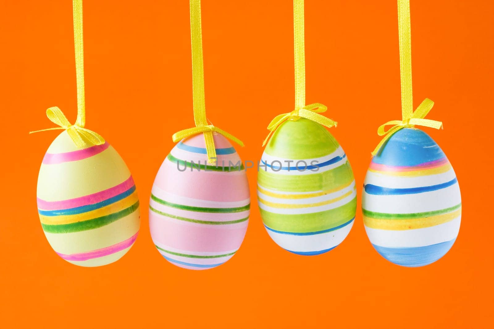 four colorful easter eggs isolated on orange background