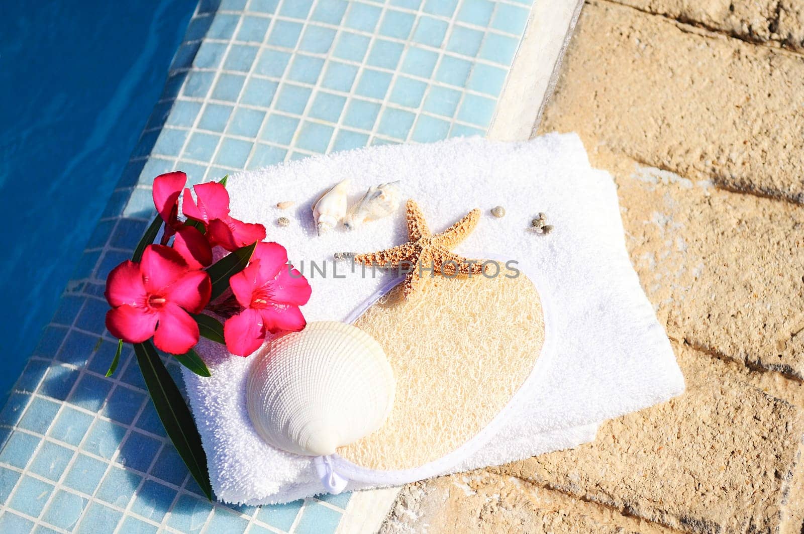 massage oil, shellfish and white towel beside a pool