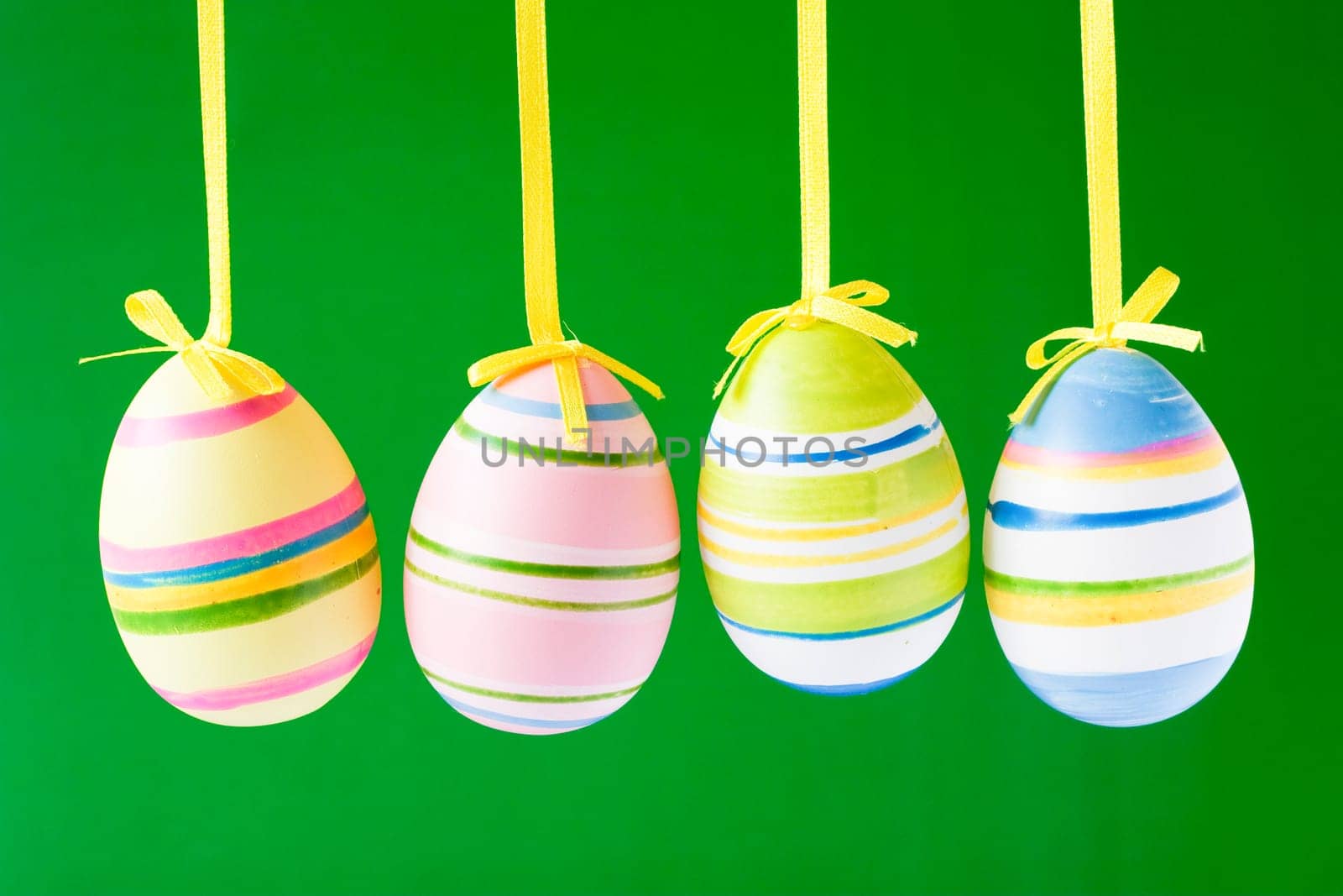 four hung easter eggs isolated on green background