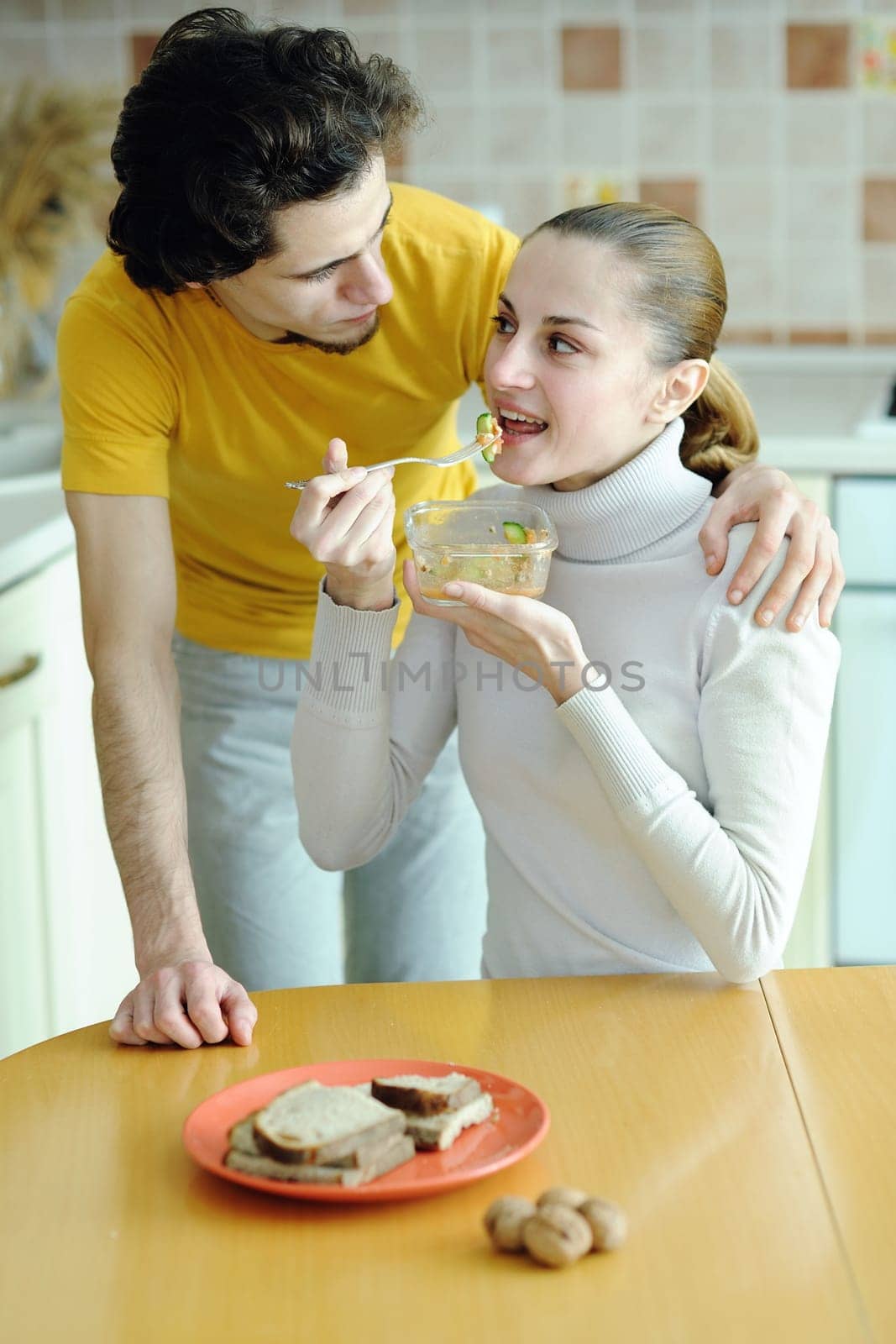 An image of young couple eating at kitchen