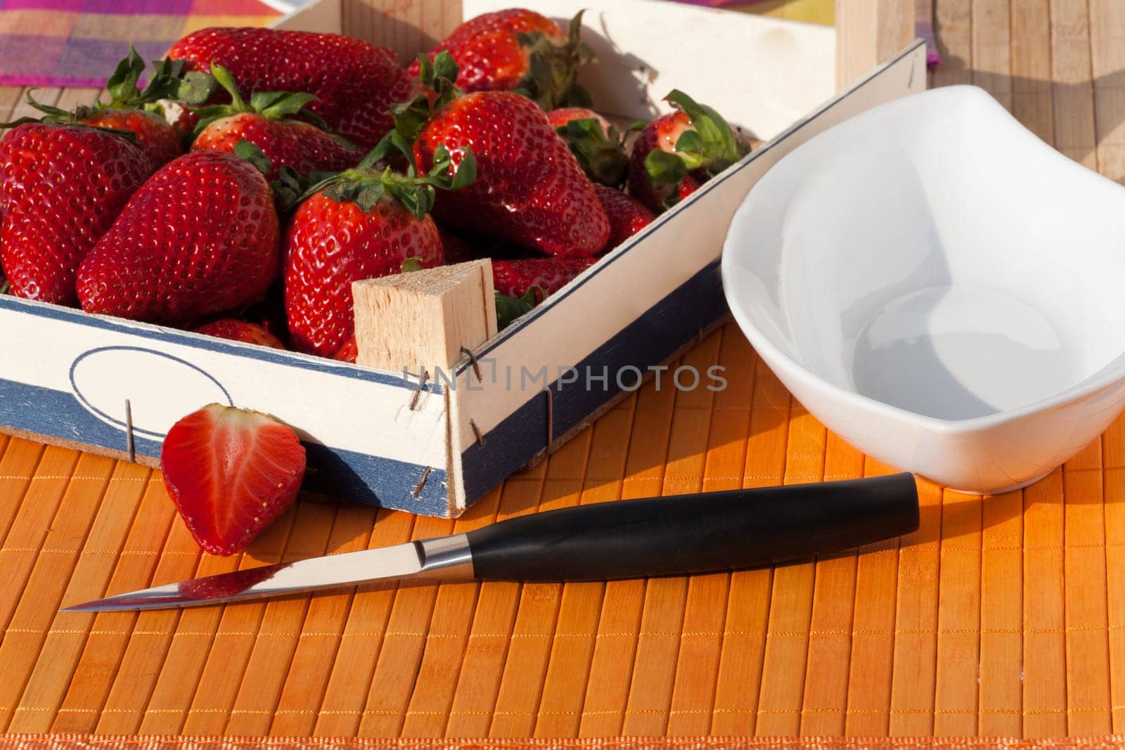 Strawberries in wooden box with peel and knife