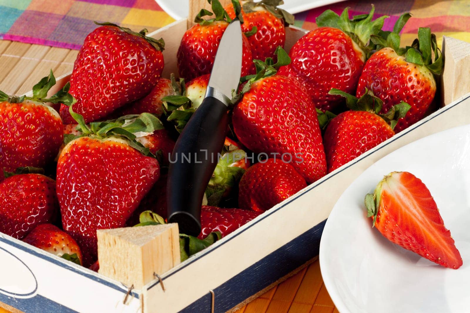 Strawberries in wooden box with peel and knife