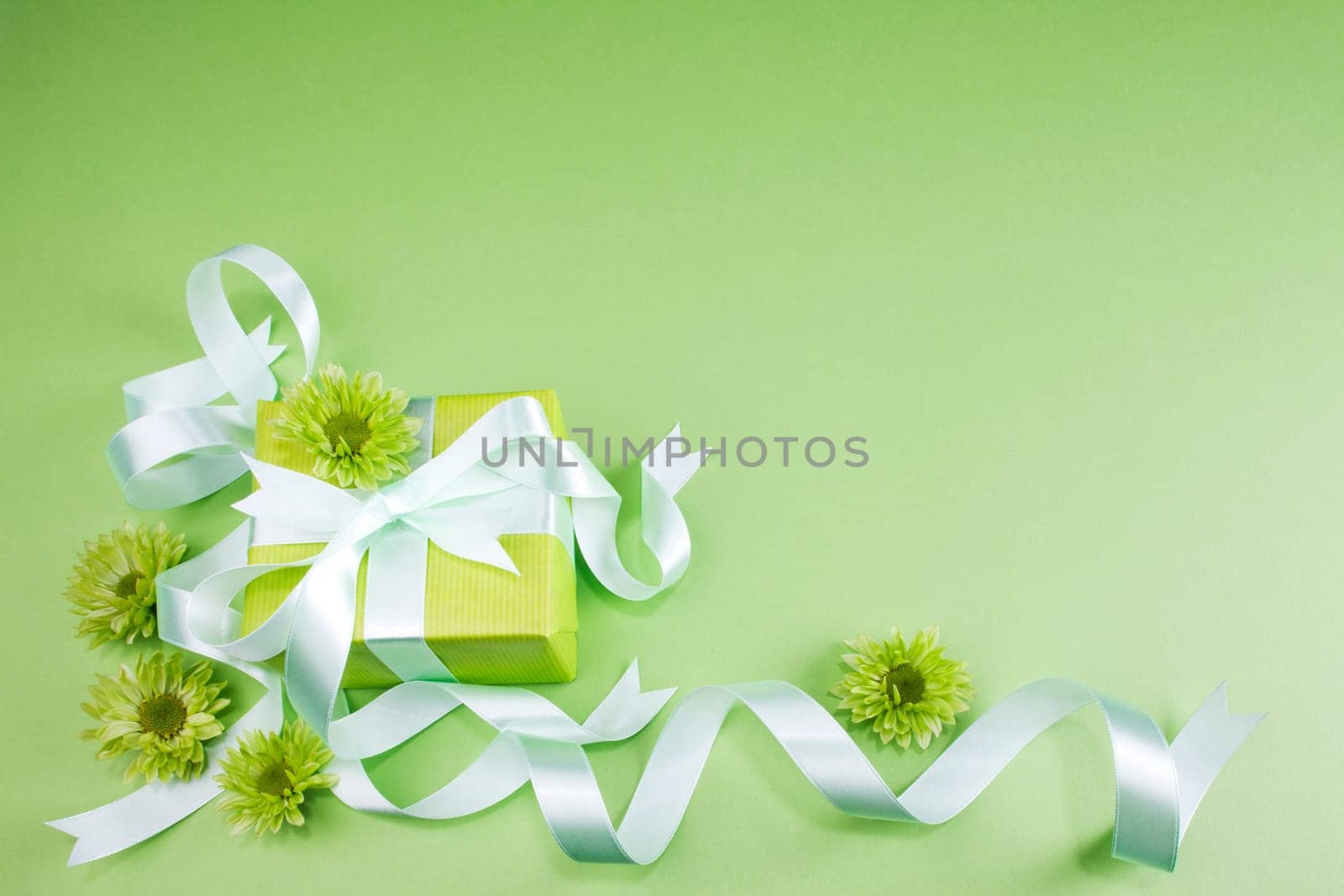 Gift box with flowers on green background