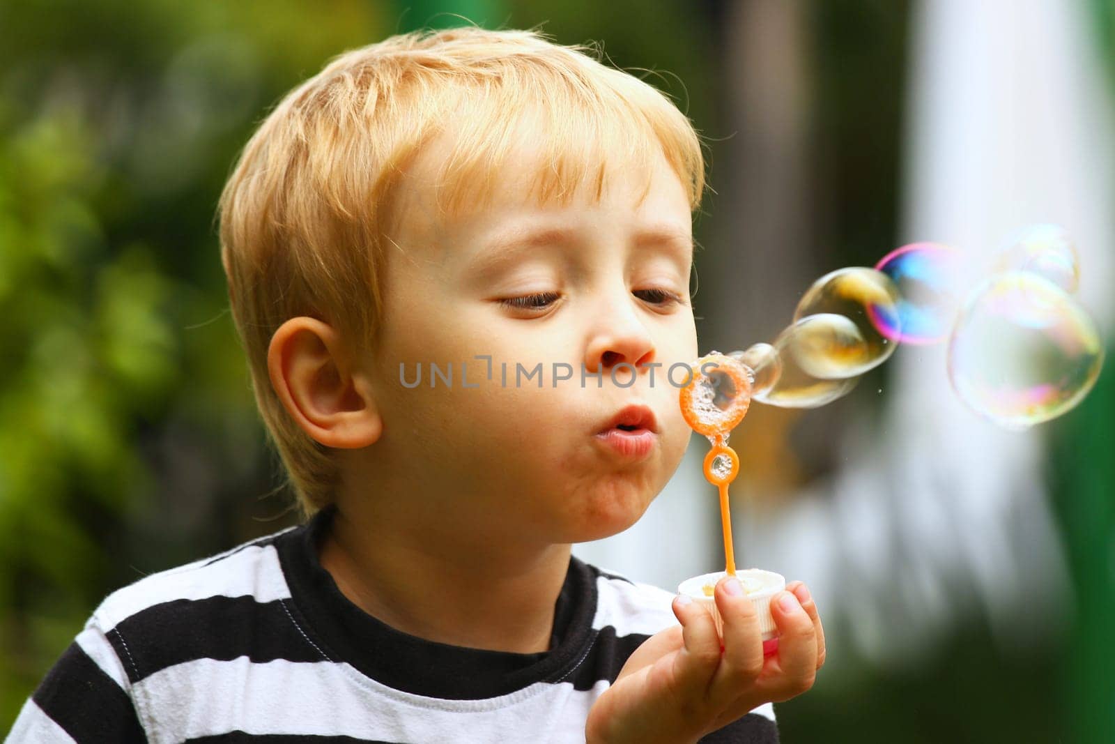 Blond boy and soap bubbles in outdoor