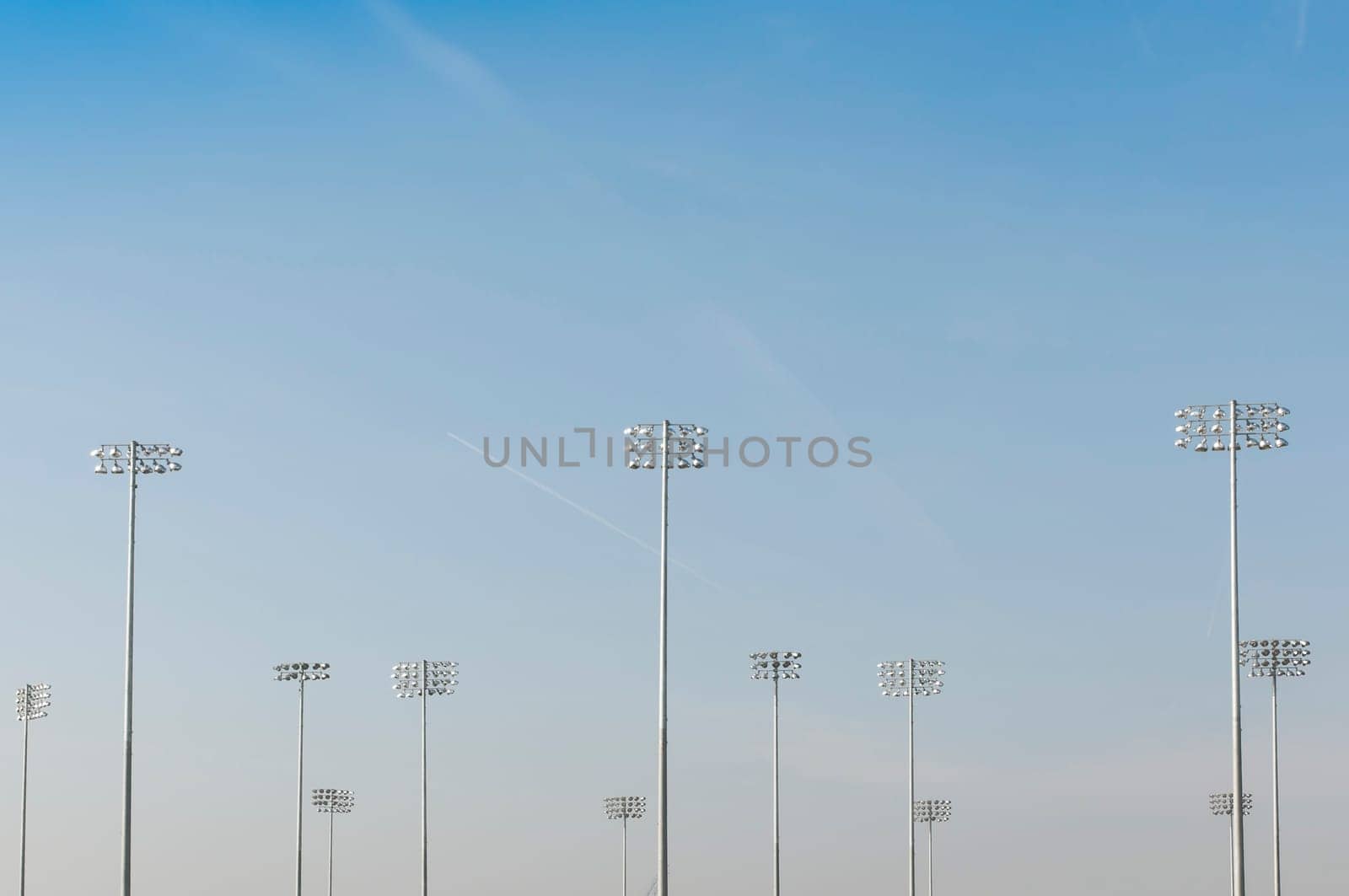 Cropped shot of illumination towers from behind, with blue sky and loads of copy space
