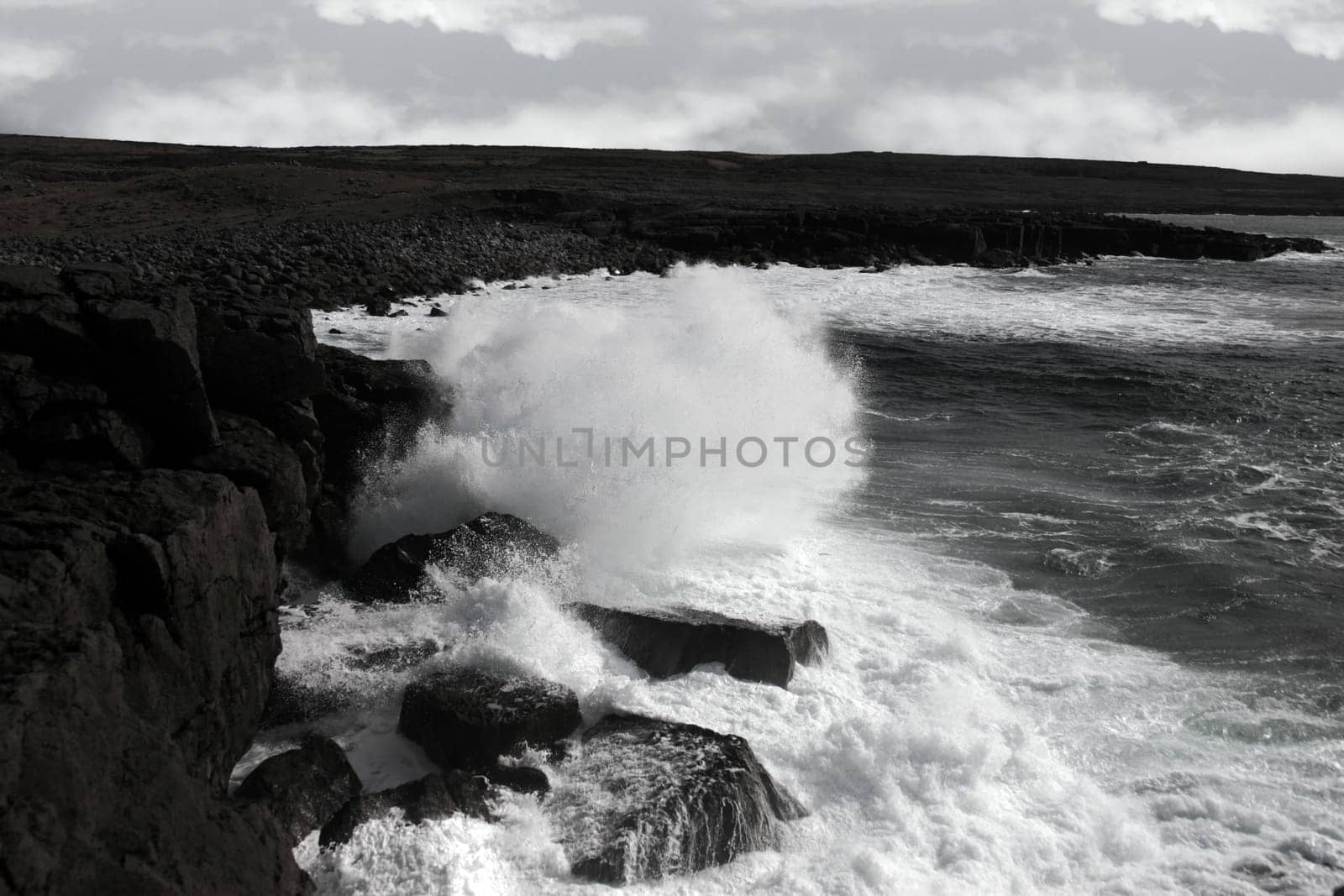 cliffs and coastline of the burren in county clare ireland with giant waves crashing on the rocks in black and white