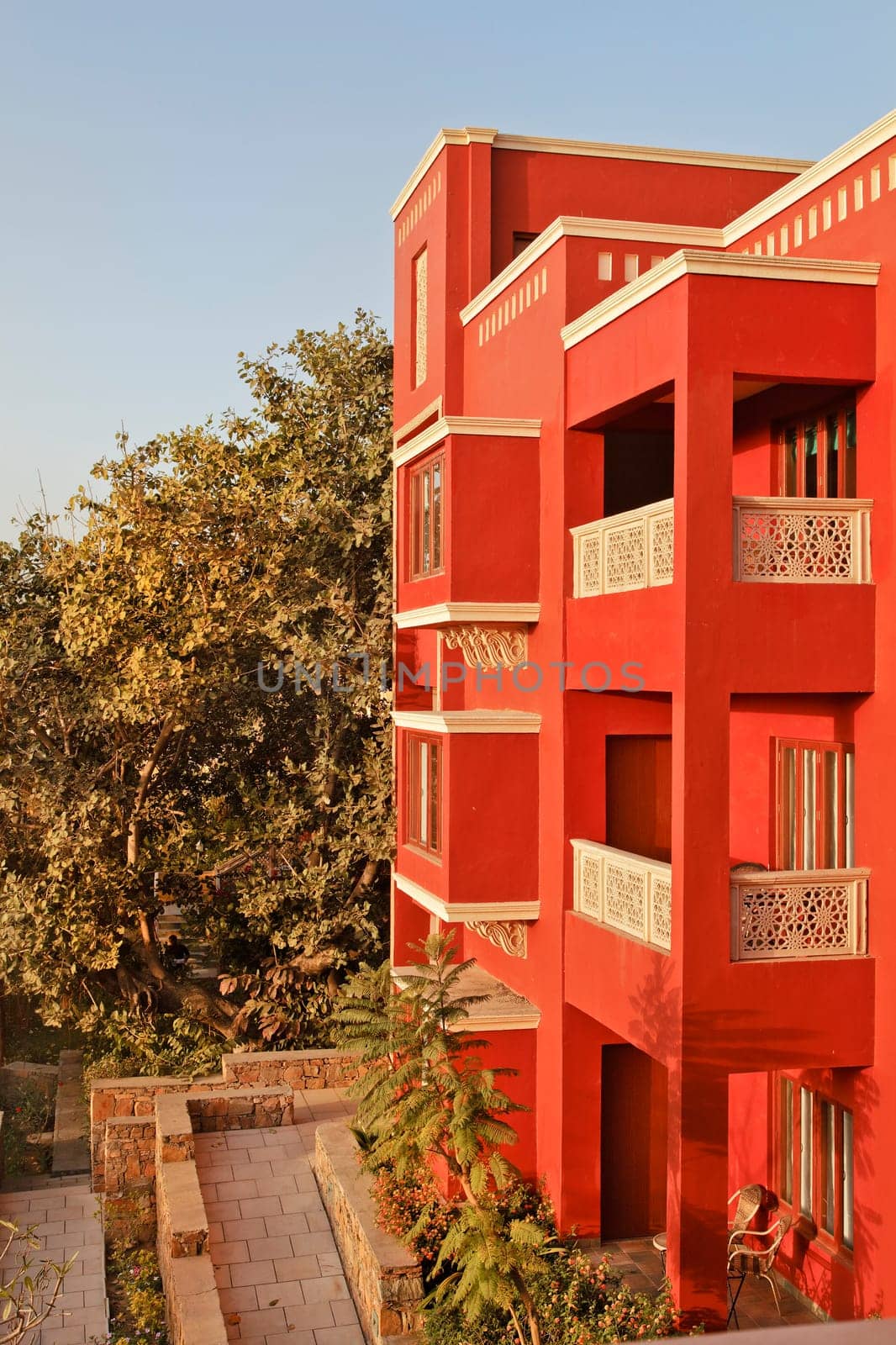 Portrait of generic modern architeture of 3 storey concrete block, brightly colored, blue sky and garden layout