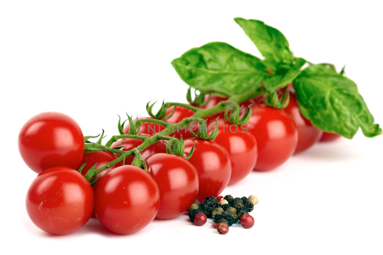 Cherry tomatoes with basil and pepper grains isolated against white background