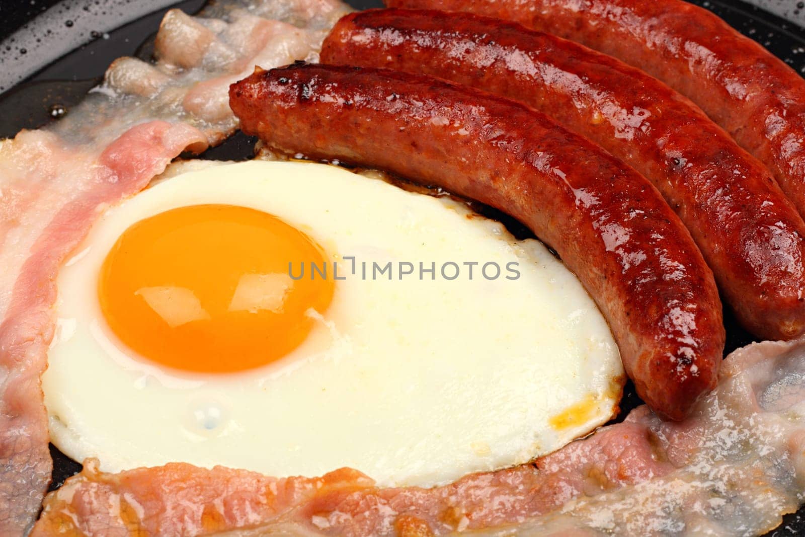 Fried egg and bacon in a frying pan.