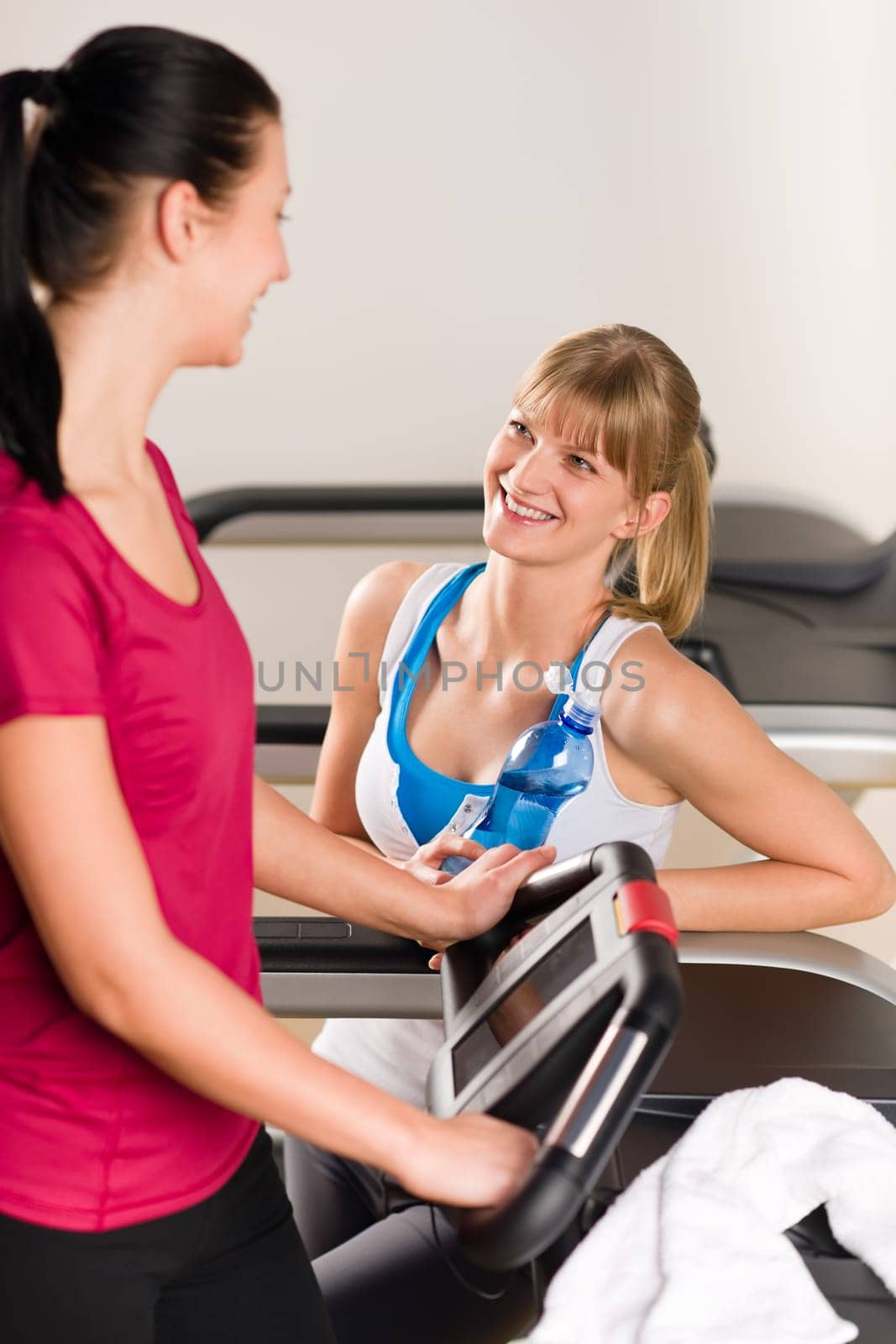 Young woman friends exercising in fitness center on treadmill machine