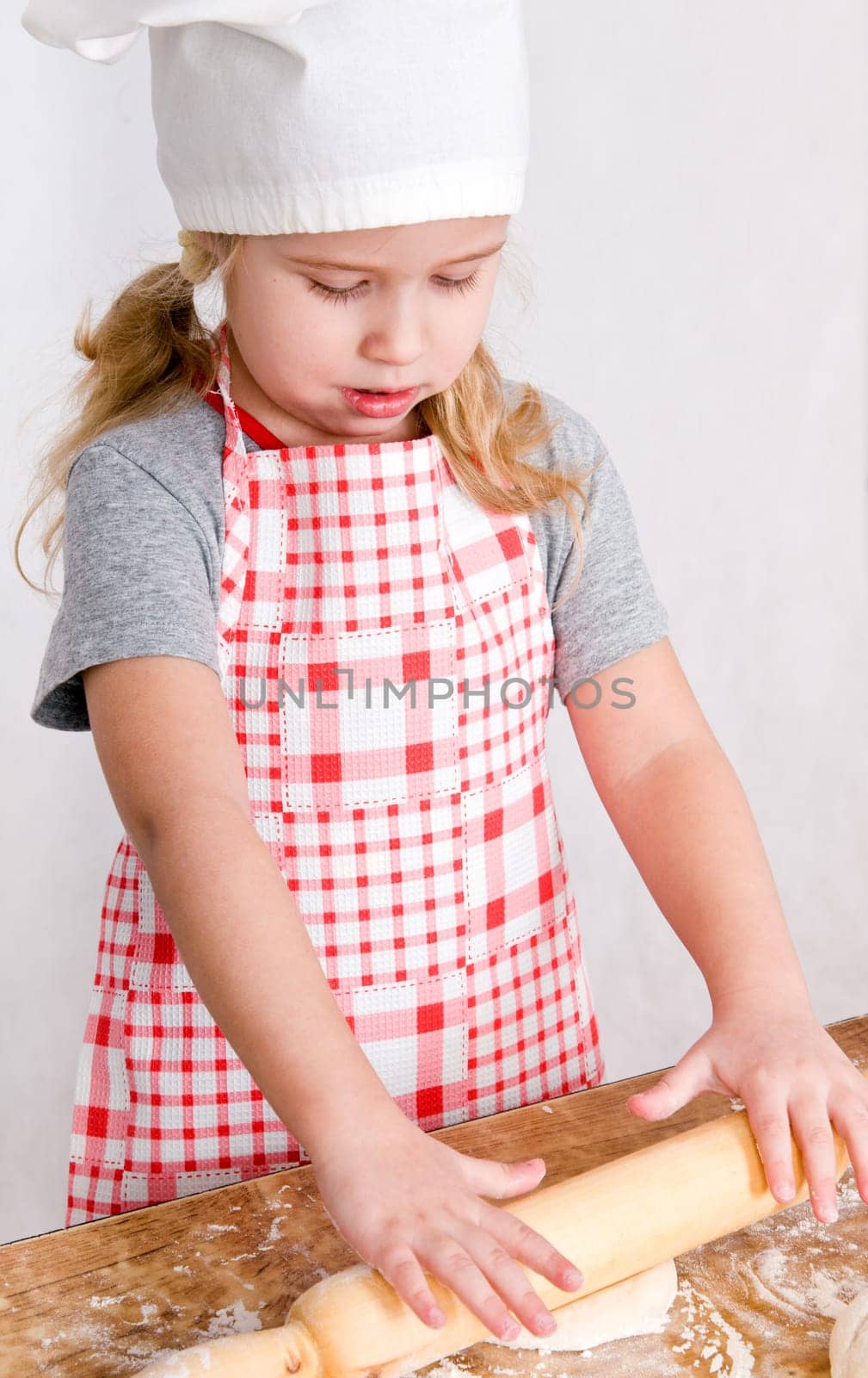 the girl in the hat chef rolls the dough