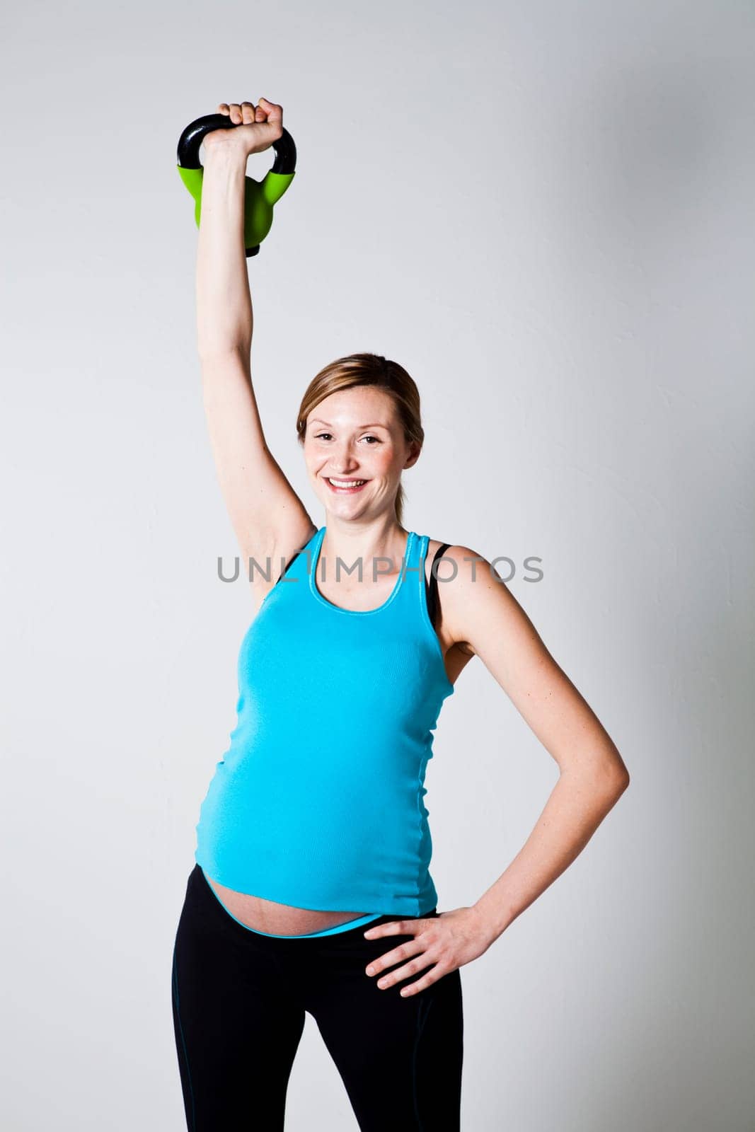 Pregnant woman doing shoulder muscle strengthening exercises with kettlebell