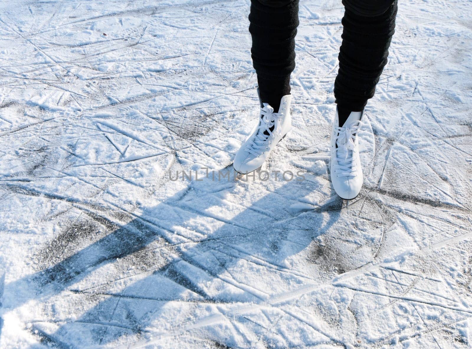 woman standing on white skates on a snowy ice floor