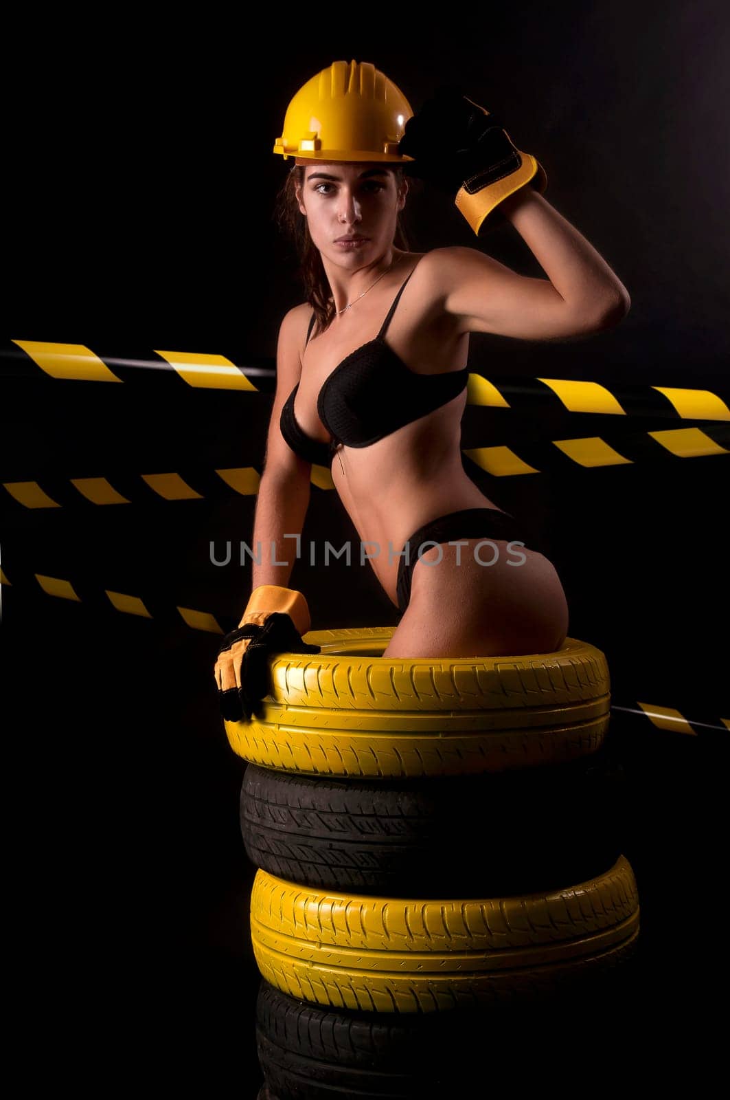 Sexy worker in lingerie posing against a dark background with tires