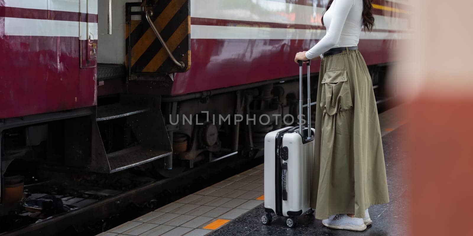 Alone Asian woman traveler with suitcase in train station platform. Summer vacation holiday and travel concept by nateemee