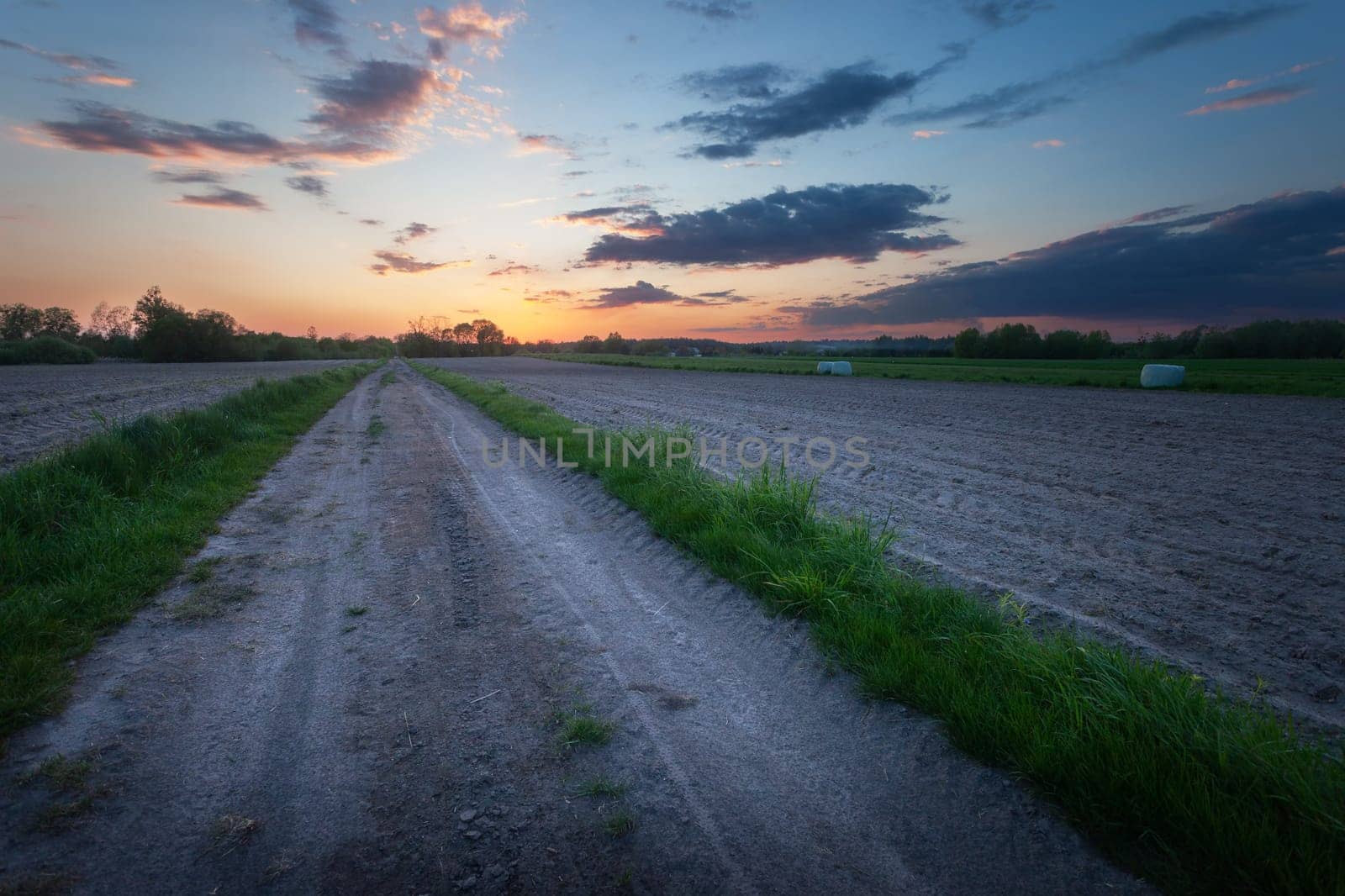 Dirt road and plowed fields with evening sky, view on a spring day by darekb22